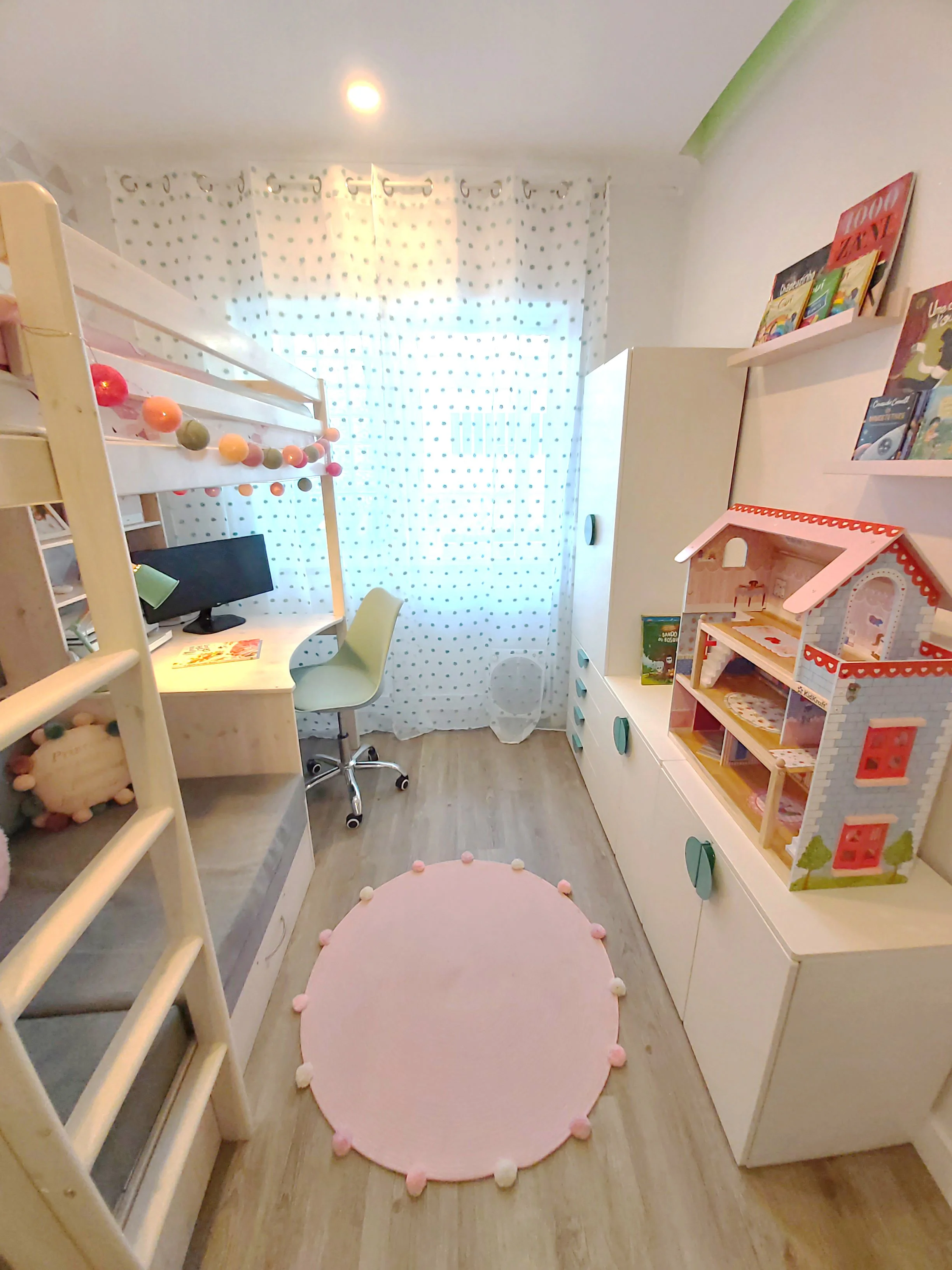 Quarto de criança decorado com cama com escada, mesa de estudo com cadeira, armário, boneca de casa de brinquedo e uma decoração delicada com cortina de cortina de bolinhas.