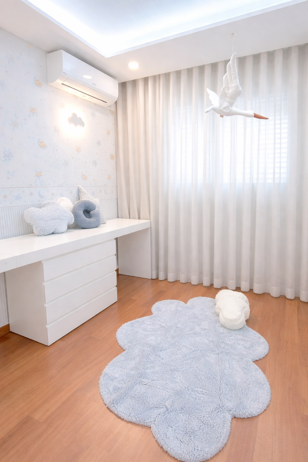 Decoração de Quarto de bebé, Alta de Lisboa, Lisboa.
Espaço decorado com cortinas brancas, tapete em formato de nuvem, papel de parede com figuras de nuvens, estrelas e mobile de cegonha suspenso. Ambiente calmo e luminoso