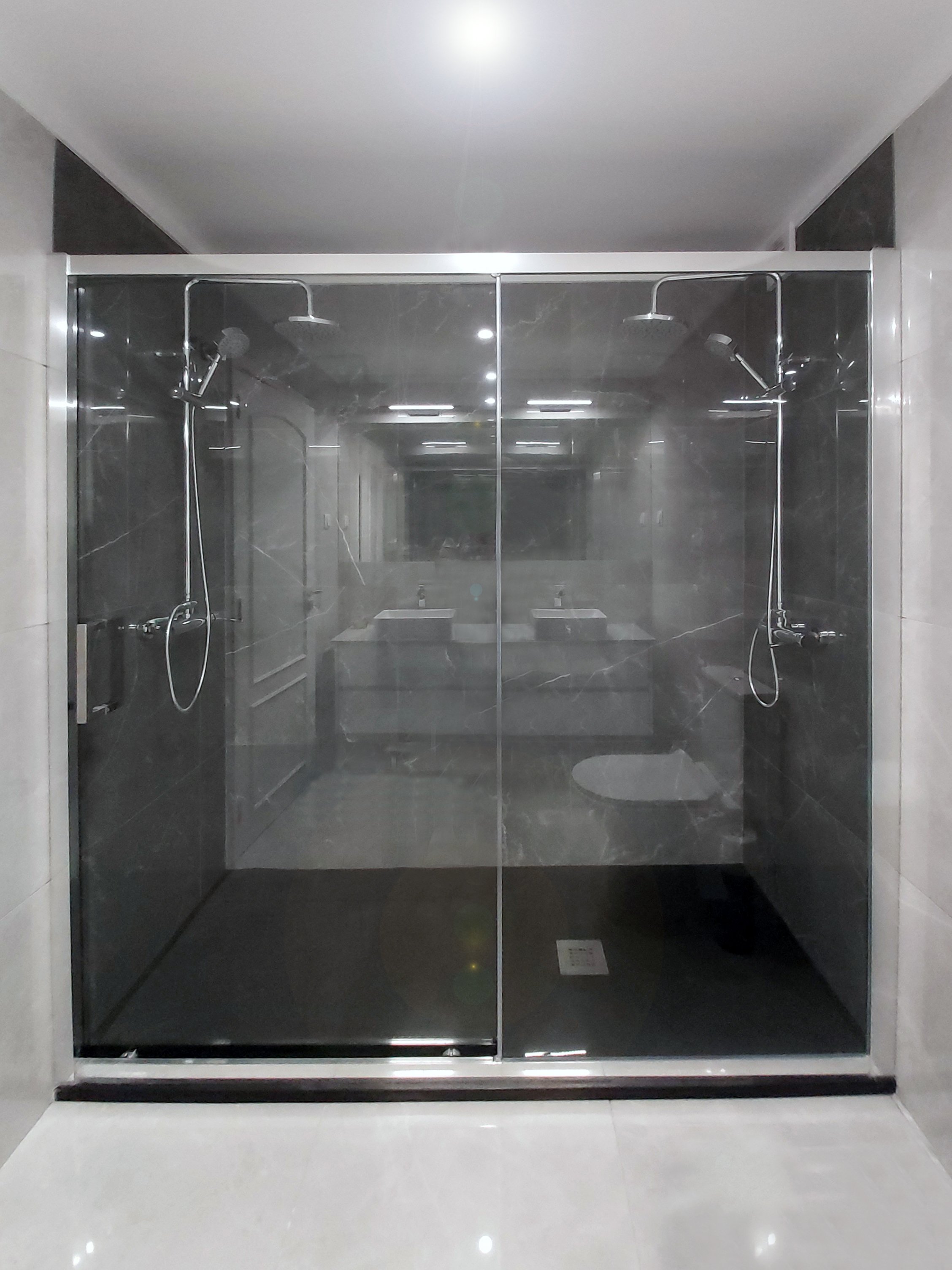 Casa de banho com revestimento de cor branca e com cabine de duche duplo e marcação de área de duche com revestimento cerâmico de cor preta