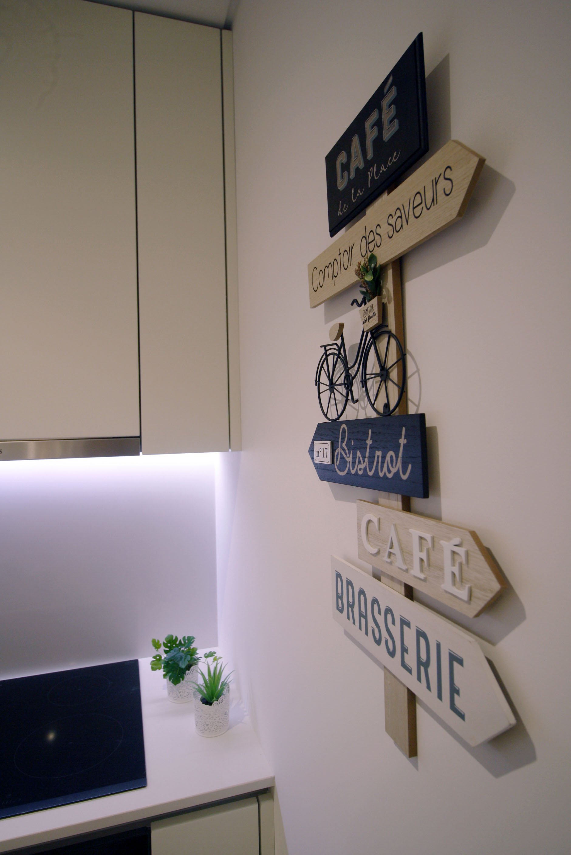 Decoração de uma parede com sinais de madeira com palavras relacionadas a cafés e brasserie, incluindo um ícone de bicicleta de metal.