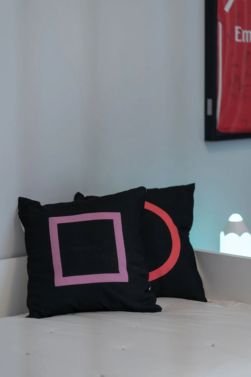 Almofadas pretas com desenhos de formas geométricas coloridas, remetendo para um ambiente gaming.