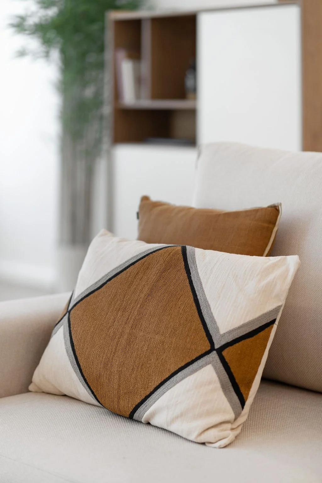 Almofadas com padrão geométrico, colocadas em um sofá claro.