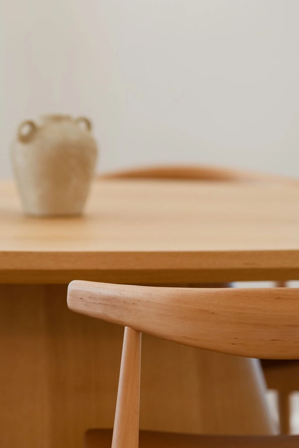 Sala de jantar minimalista com mesa de madeira oval, com cadeira (pormenor)