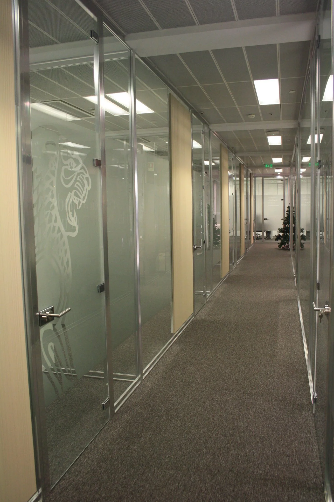 Corredor com divisória em vidro, decoradas a vinil frost e apontamentos revestidos a vescom.