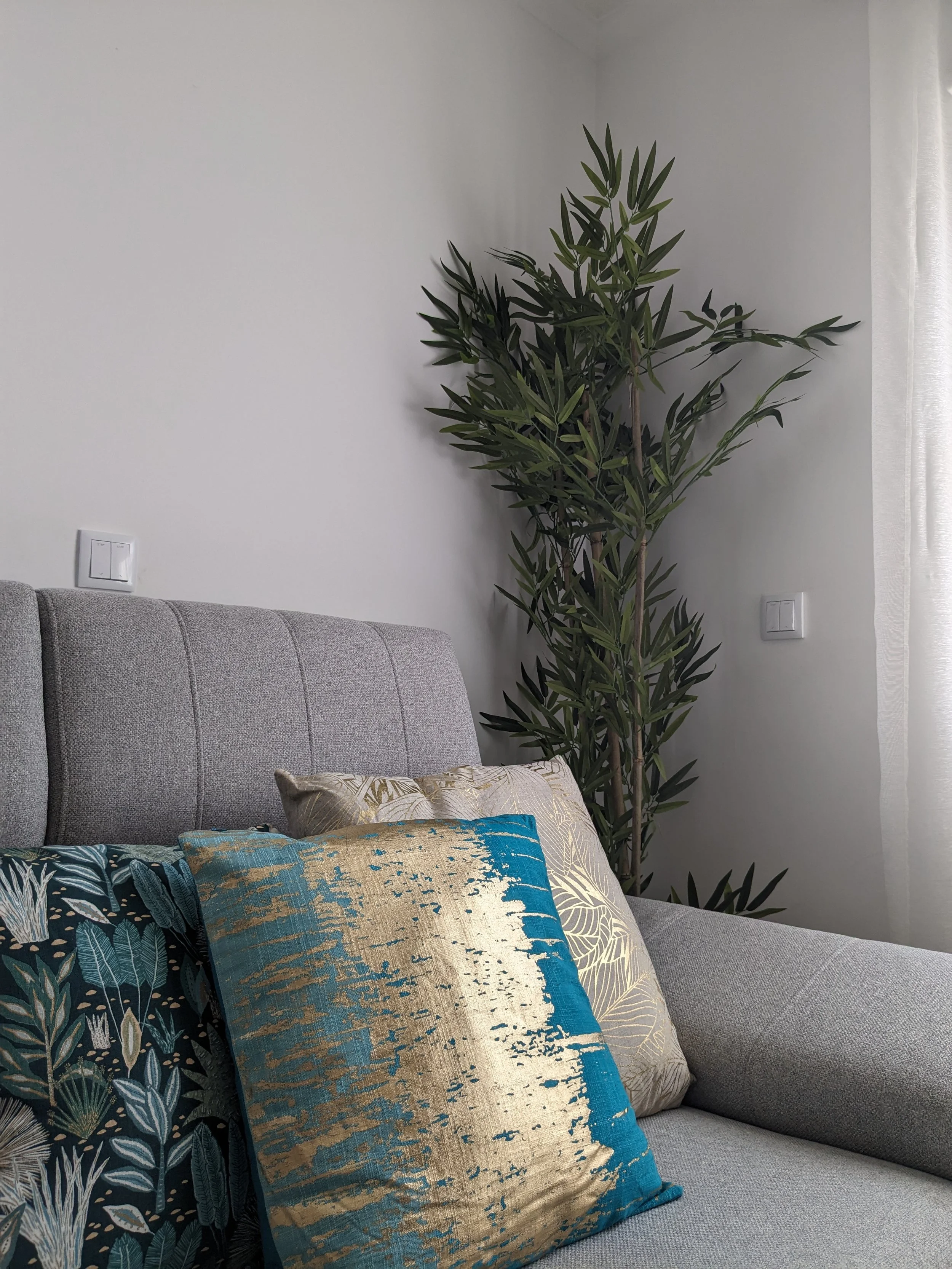 Decoração de Sala, Amadora.
Pormenor de Sofá cinza com várias almofadas decorativas de diferentes cores e padrões.
