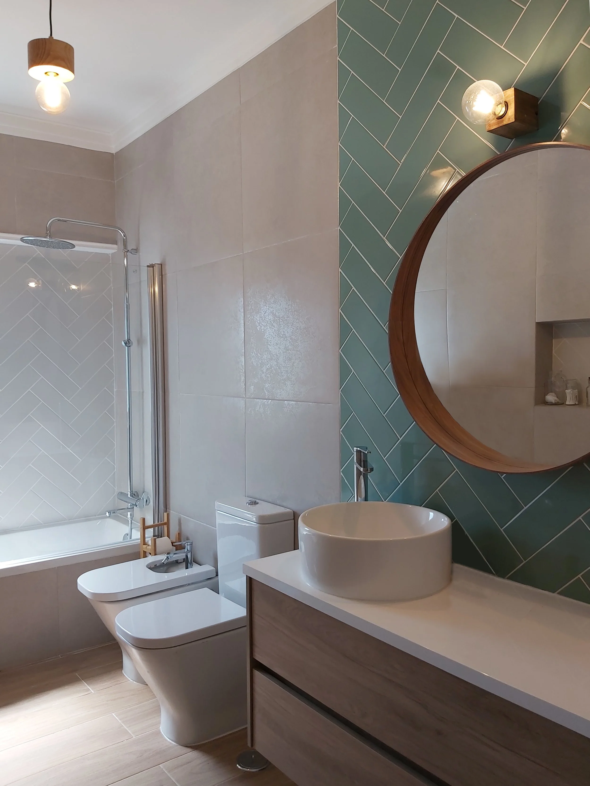 Casa-de-banho com apontamentos em madeira, e destaque de parede de lavatório com revestimento em azulejos com colocação em espinha