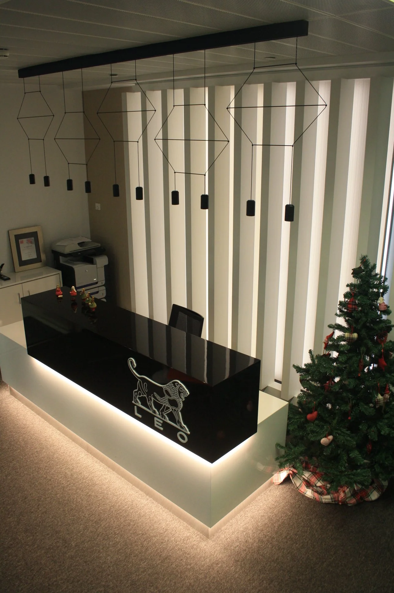 Balcão de recepção com iluminação integrada, candeeiro suspenso e painel ripado retro iluminado.