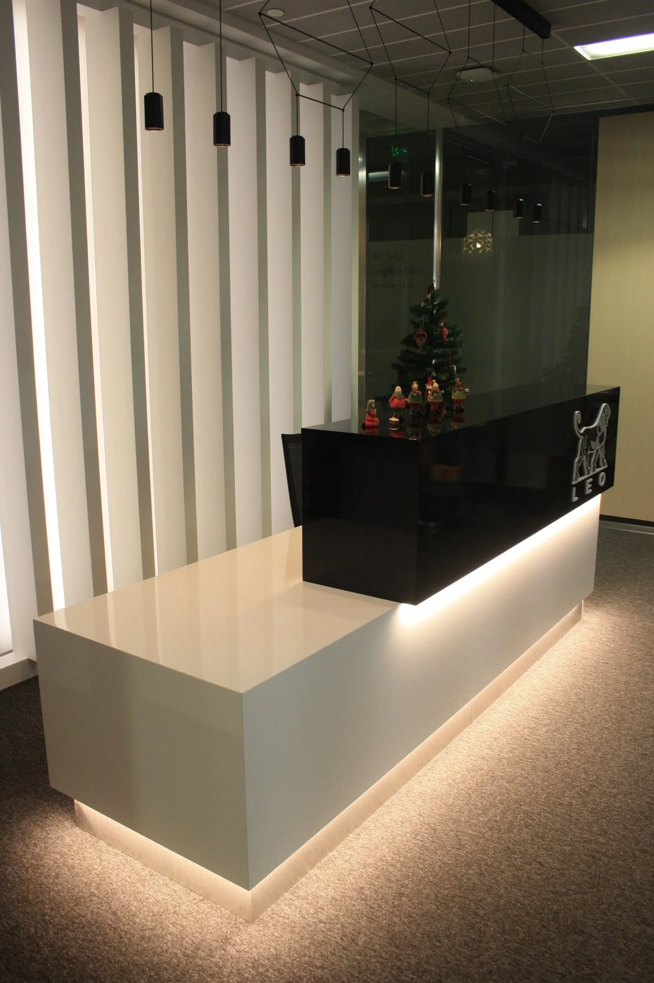 Balcão de recepção com iluminação integrada, candeeiro suspenso e painel ripado retro iluminado.