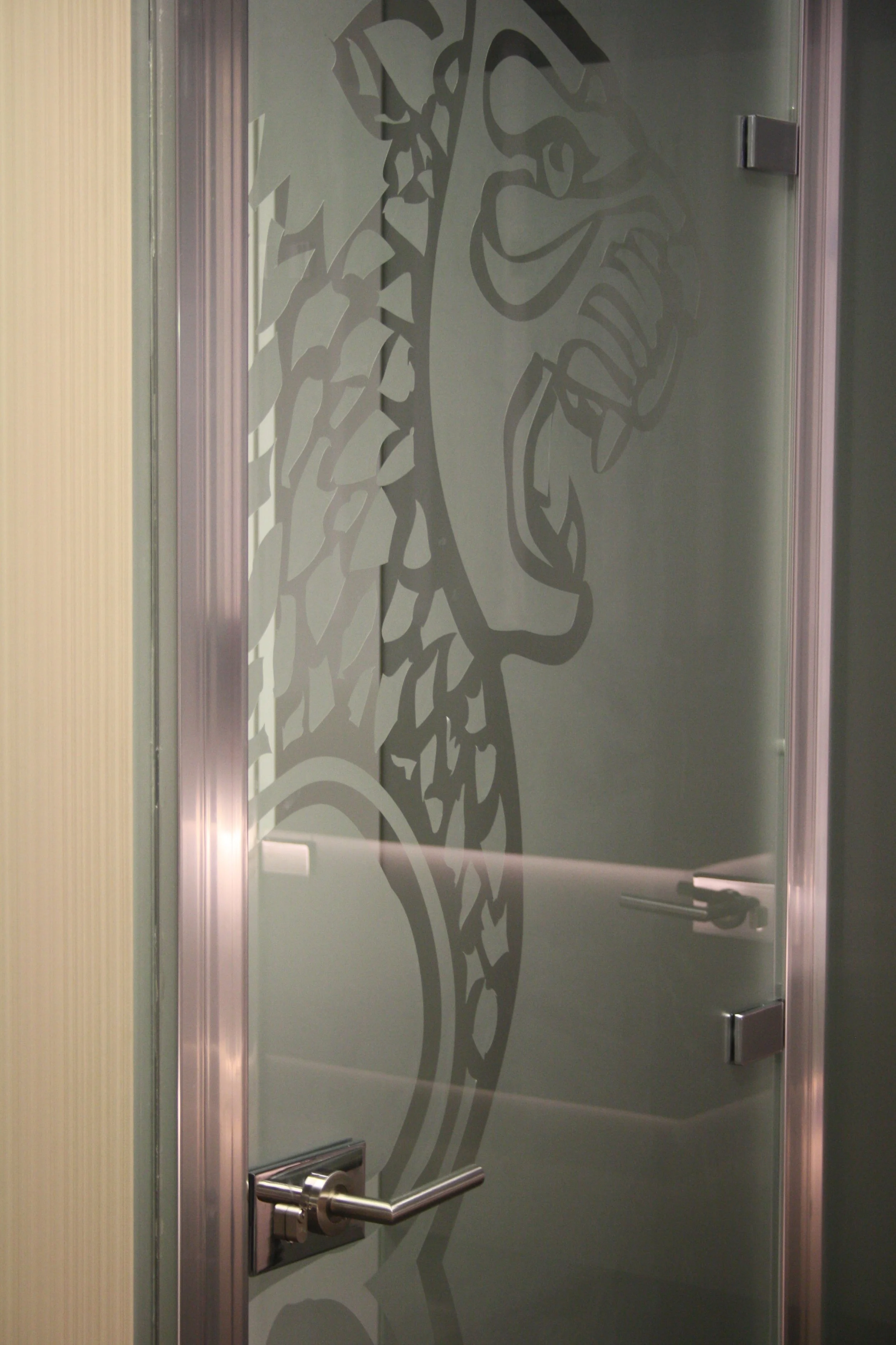 Divisória em vidro, decorada a vinil frost com logomarca recortada.