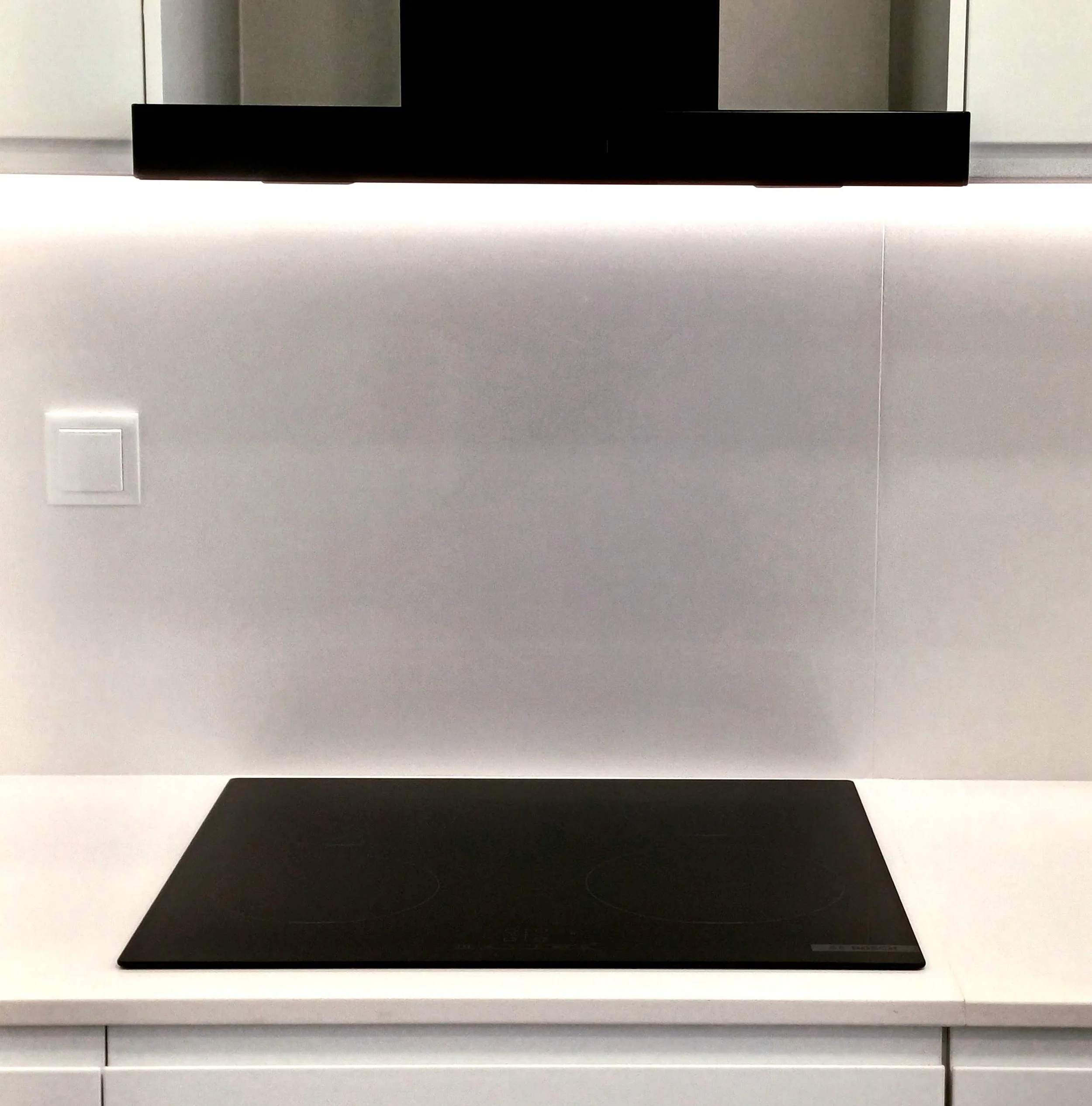Remodelação de Cozinha no Parque das Nações, Lisboa. Cozinha com Decoração Preto/Branco, armários brancos mate com puxador integrado, tampo e back-splash em silstone branco. Equipamentos em cor preta.