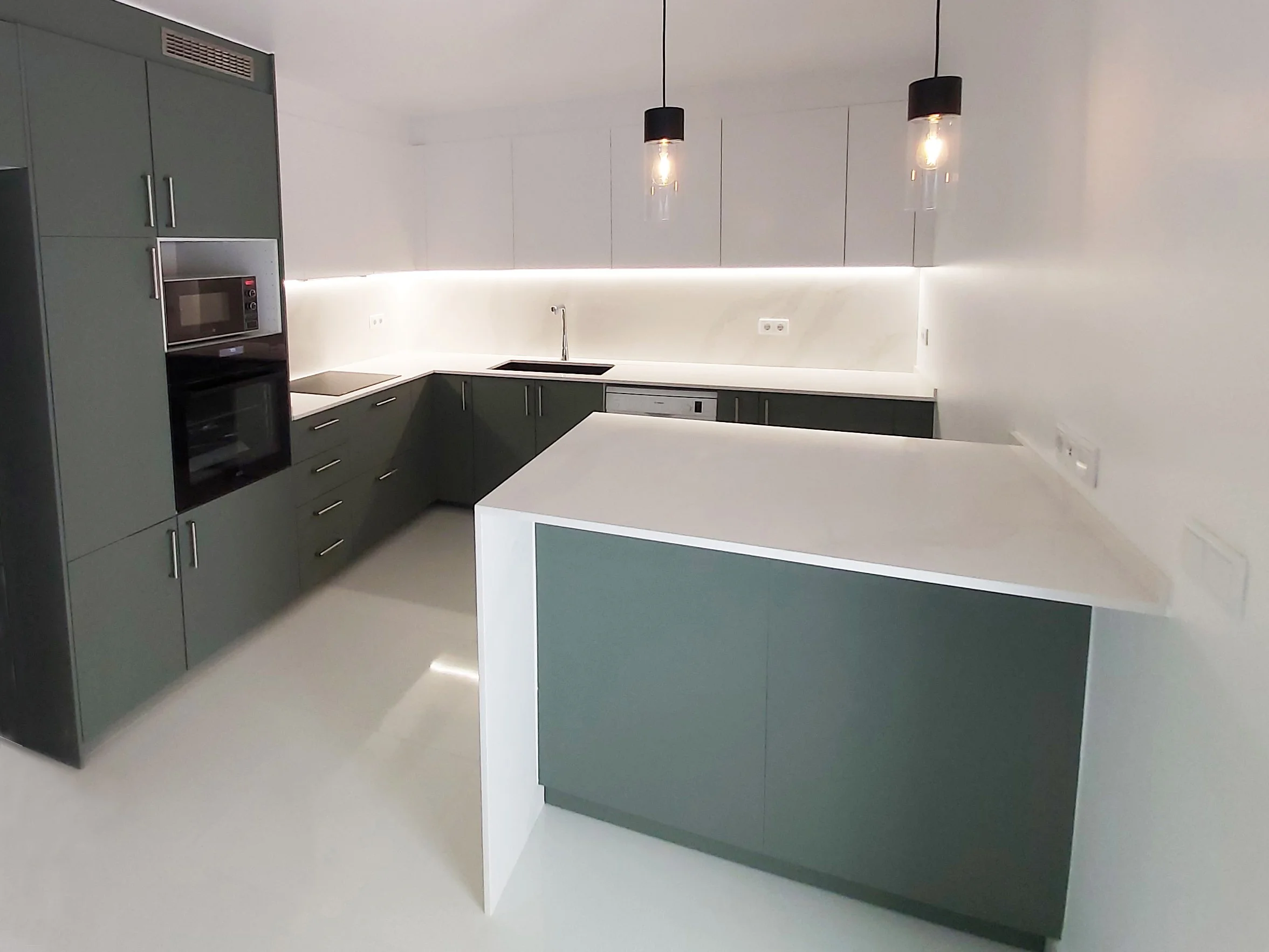 Cozinha com península e tampos e backsplash em silstone calacatta gold. Iluminação suspensa e indireta