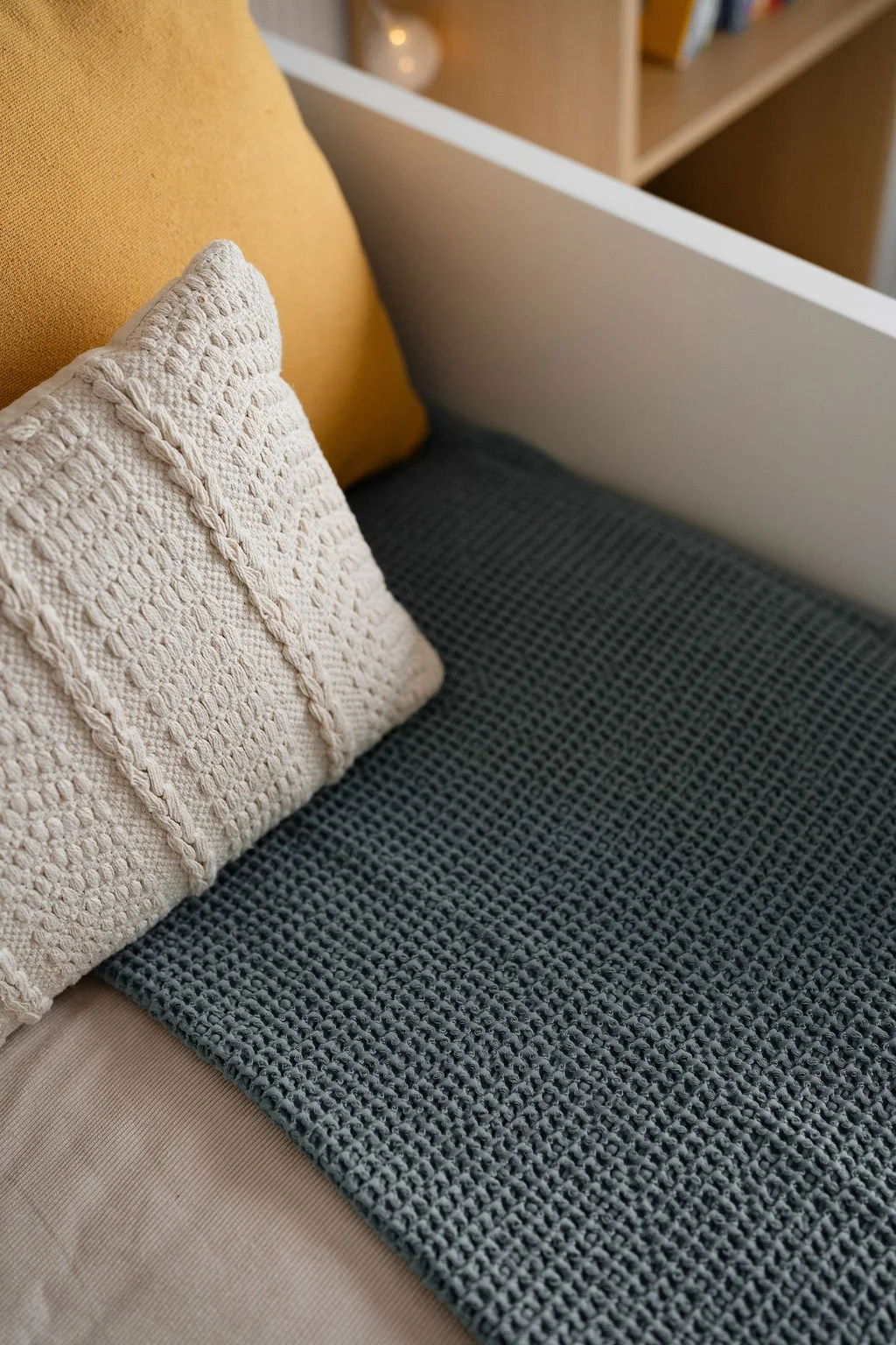 Cores e texturas de uma poltrona com almofadas brancas e amarelas decorativas.