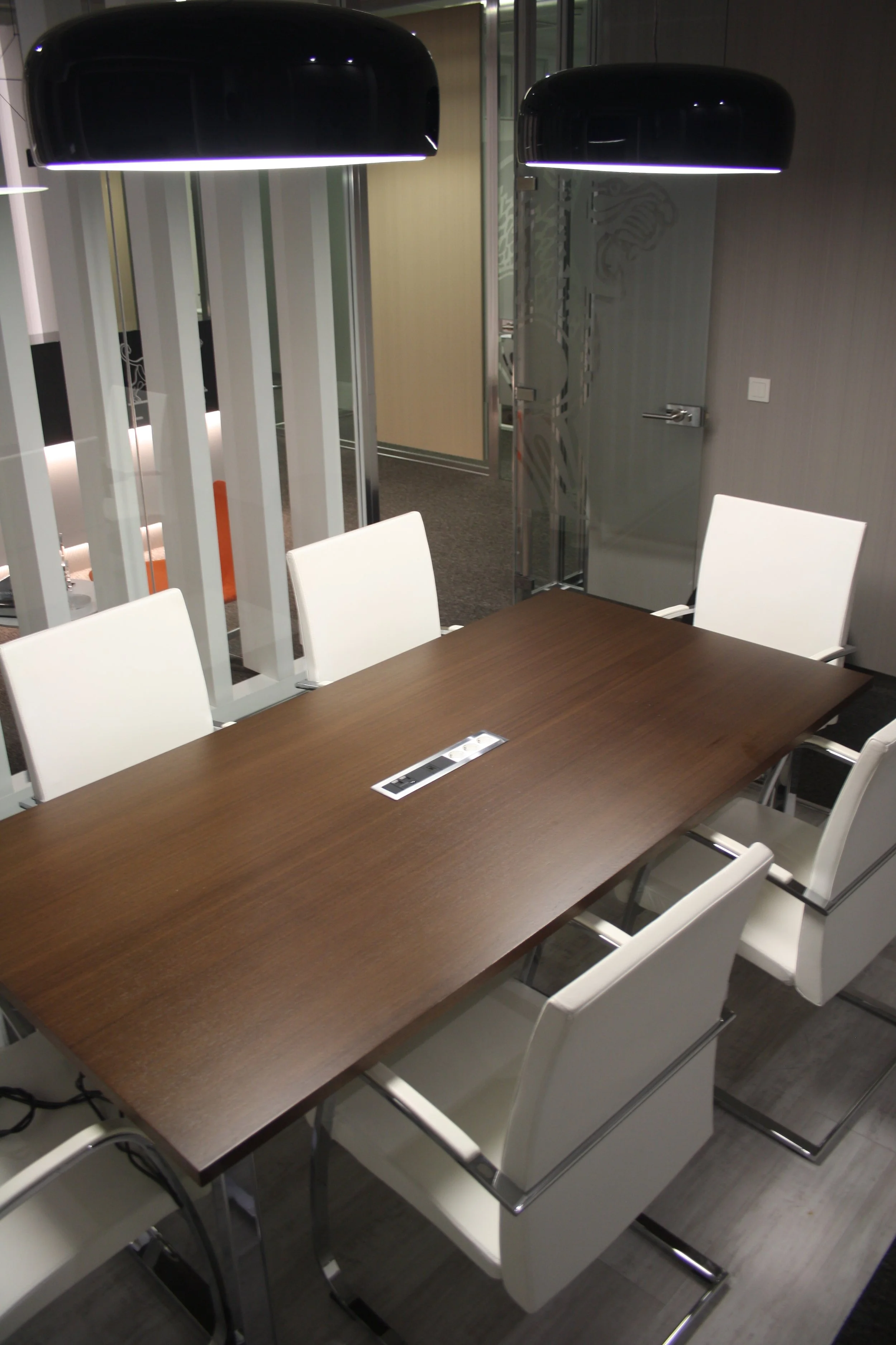 Sala de reuniões com candeeiros de teto e cadeiras estofadas a pele branca