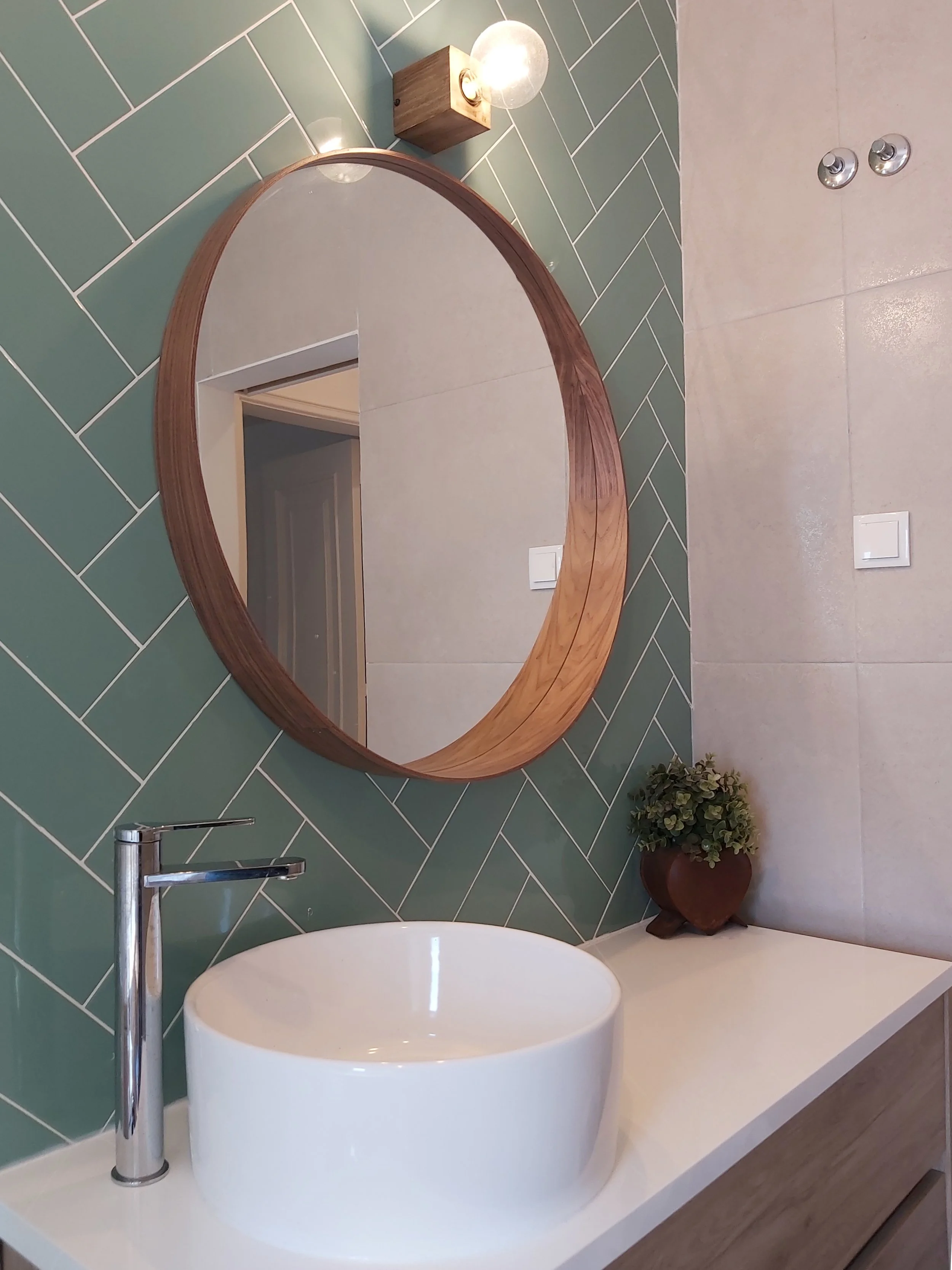 Casa-de-banho com apontamentos em madeira, e destaque de parede de lavatório com revestimento em azulejos com colocação em espinha