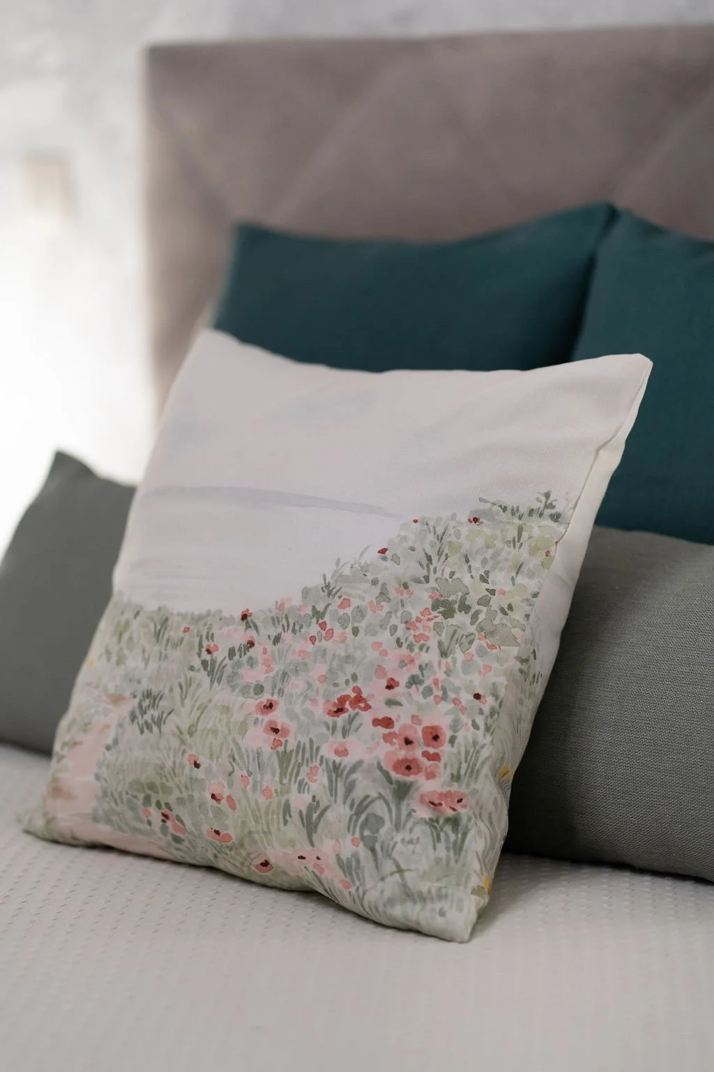 Travesseiro decorativo com estampa de flores em cama com outros travesseiros