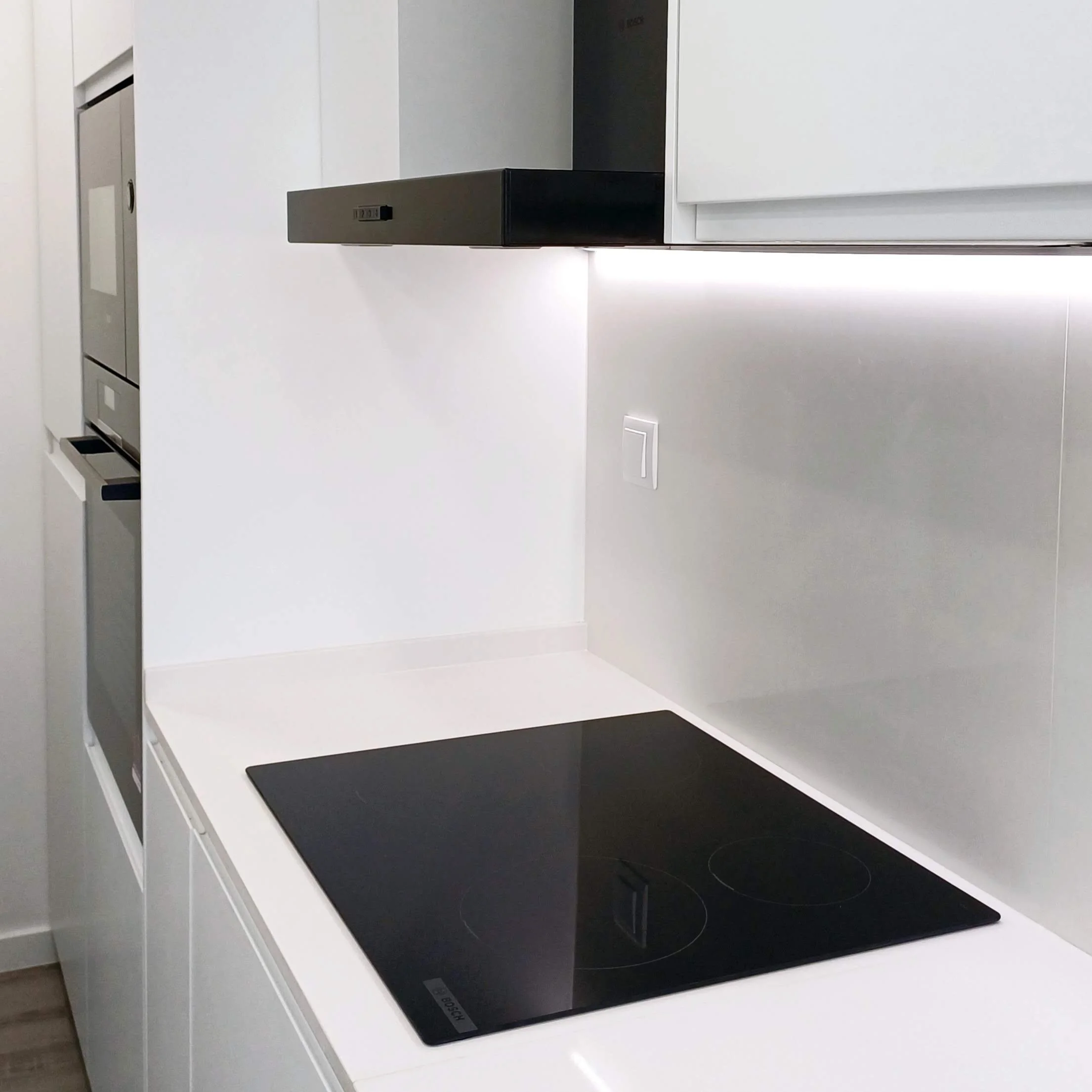 	
Remodelação de Cozinha no Parque das Nações, Lisboa. Cozinha com Decoração Preto/Branco, Pavimento vinílico imitação de madeira cinza, armários brancos mate com puxador integrado, tampo e back-splash em silstone branco. Equipamentos em cor preta.