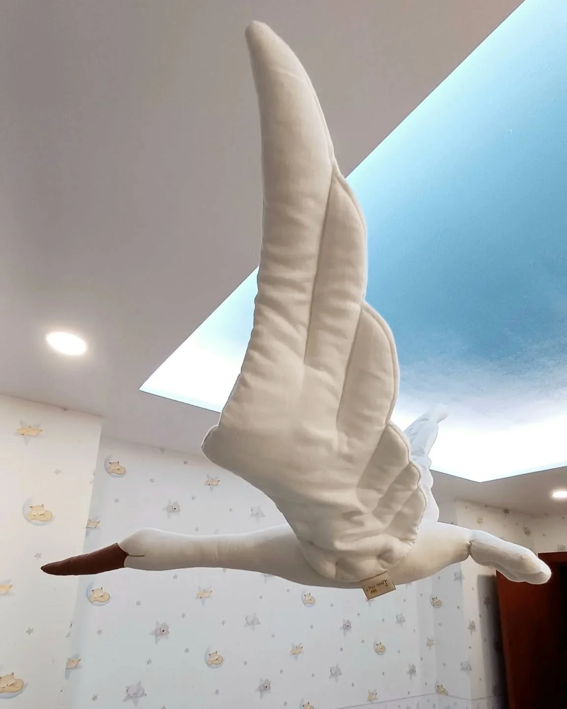 Boneco em formato de cisne feito de tecido, pendurado no teto de um ambiente infantil.
