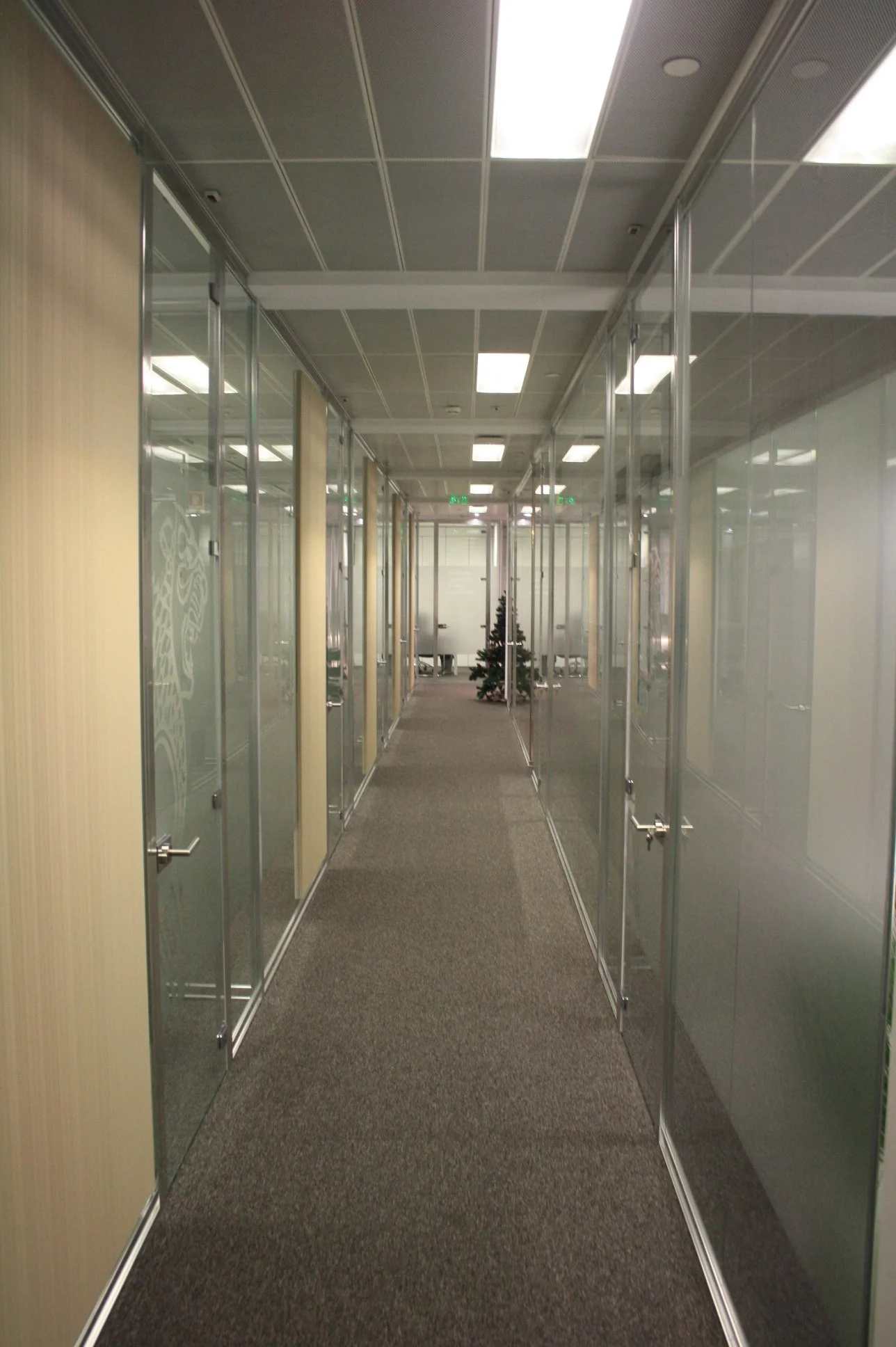 Corredor com divisória em vidro, decoradas a vinil frost e apontamentos revestidos a vescom.