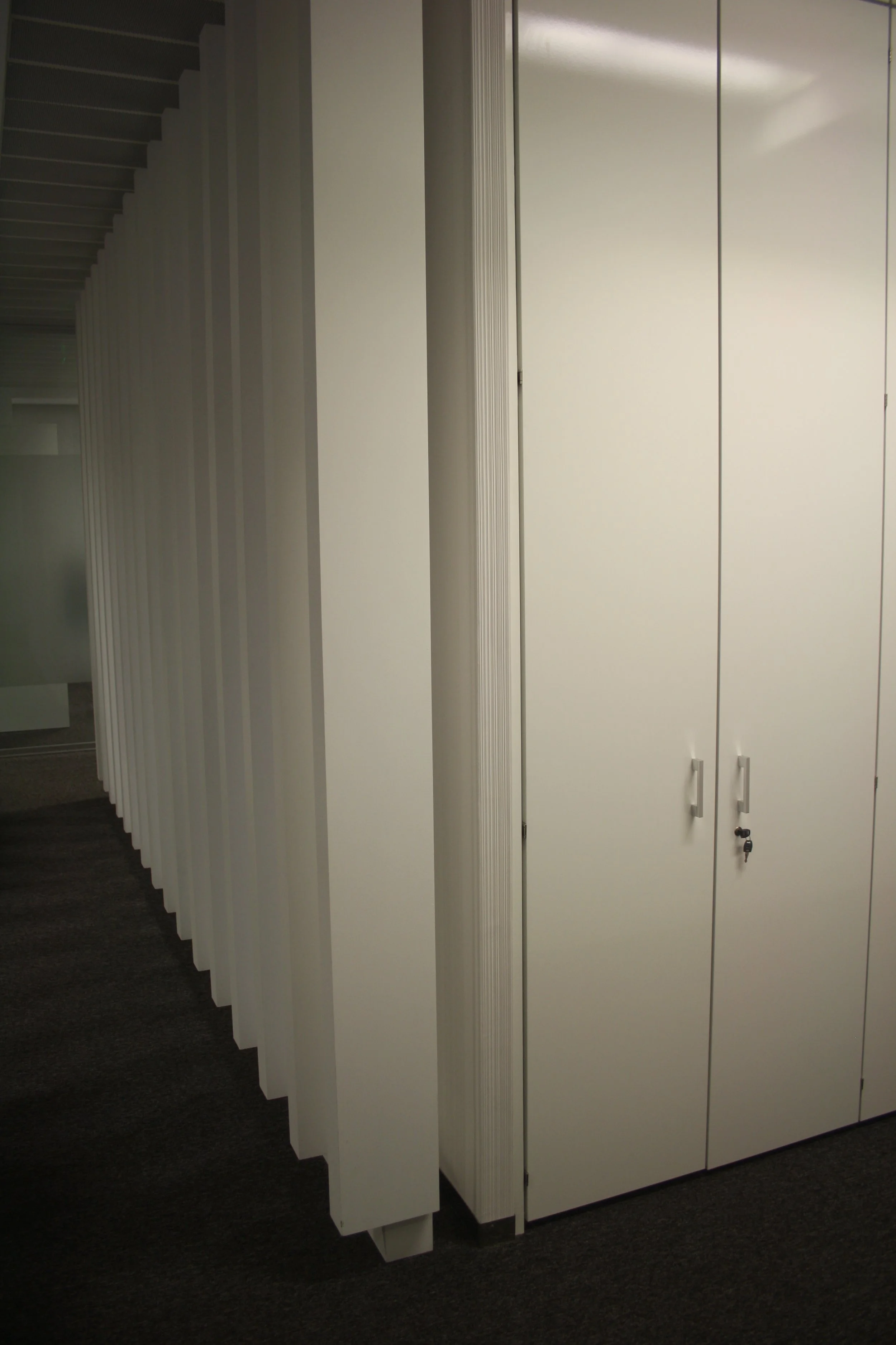 Divisória em ripado e armários de arrumação.