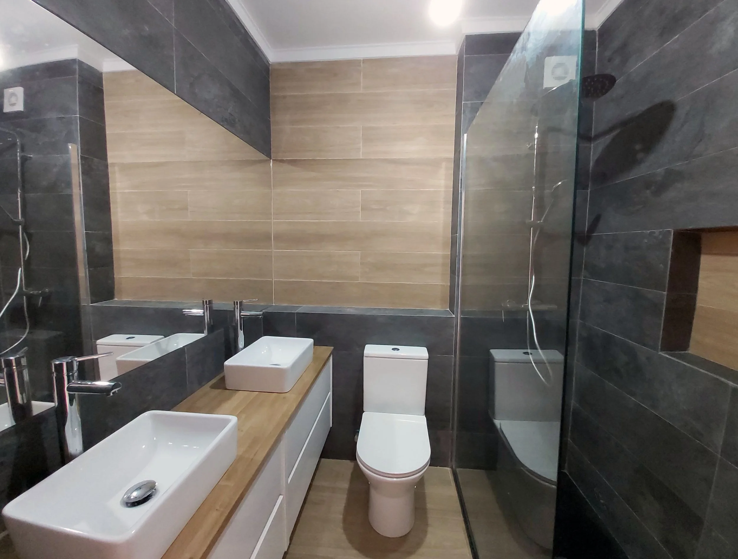 Casa-de-banho com pavimento e apontamentos em cerâmica imitação de madeira, e restante revestimento em azulejos imitação xisto