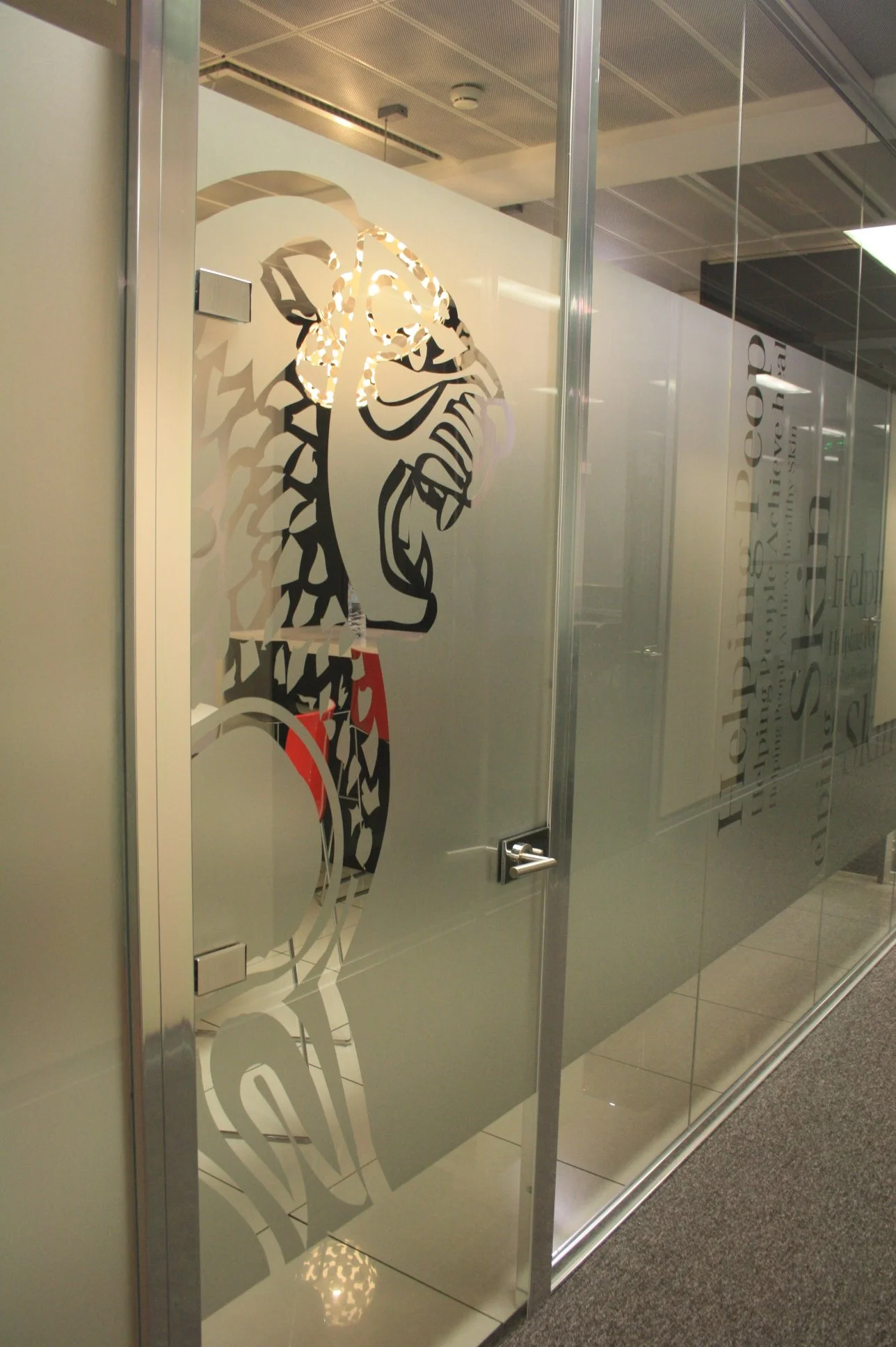 Divisória em vidro, decorada a vinil frost com logomarca recortada.