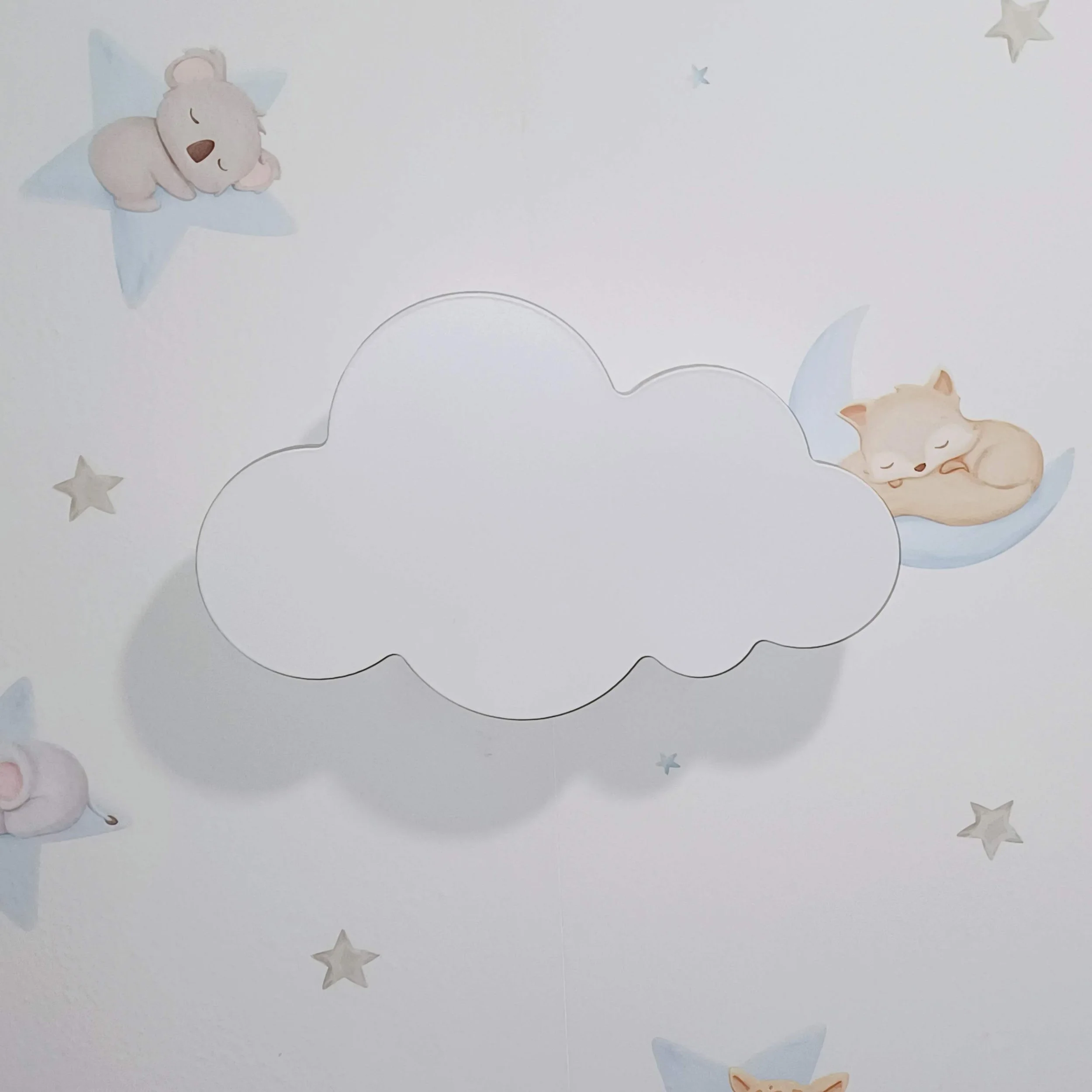 Parede de quarto infantil com desenhos de um urso dormindo na estrela e um gato dormindo na lua, com estrelas e nuvens coloridas ao redor.