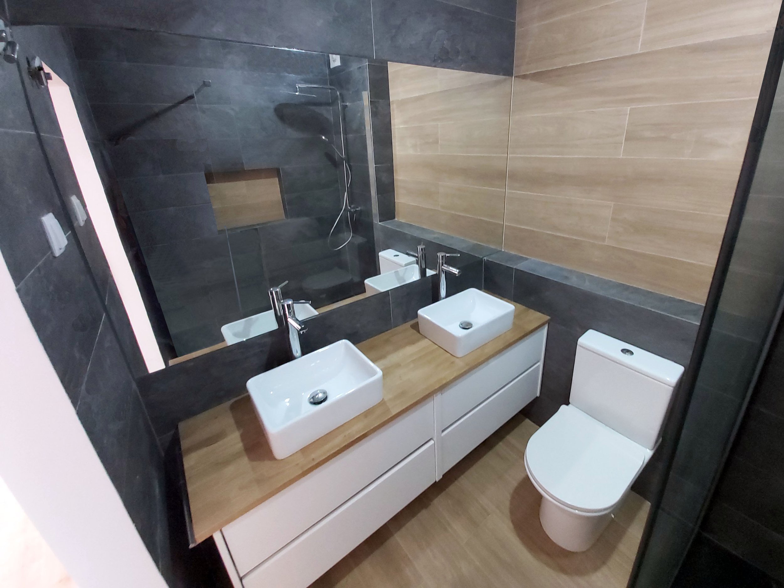 Casa-de-banho com pavimento e apontamentos em cerâmica imitação de madeira, e restante revestimento em azulejos imitação xisto