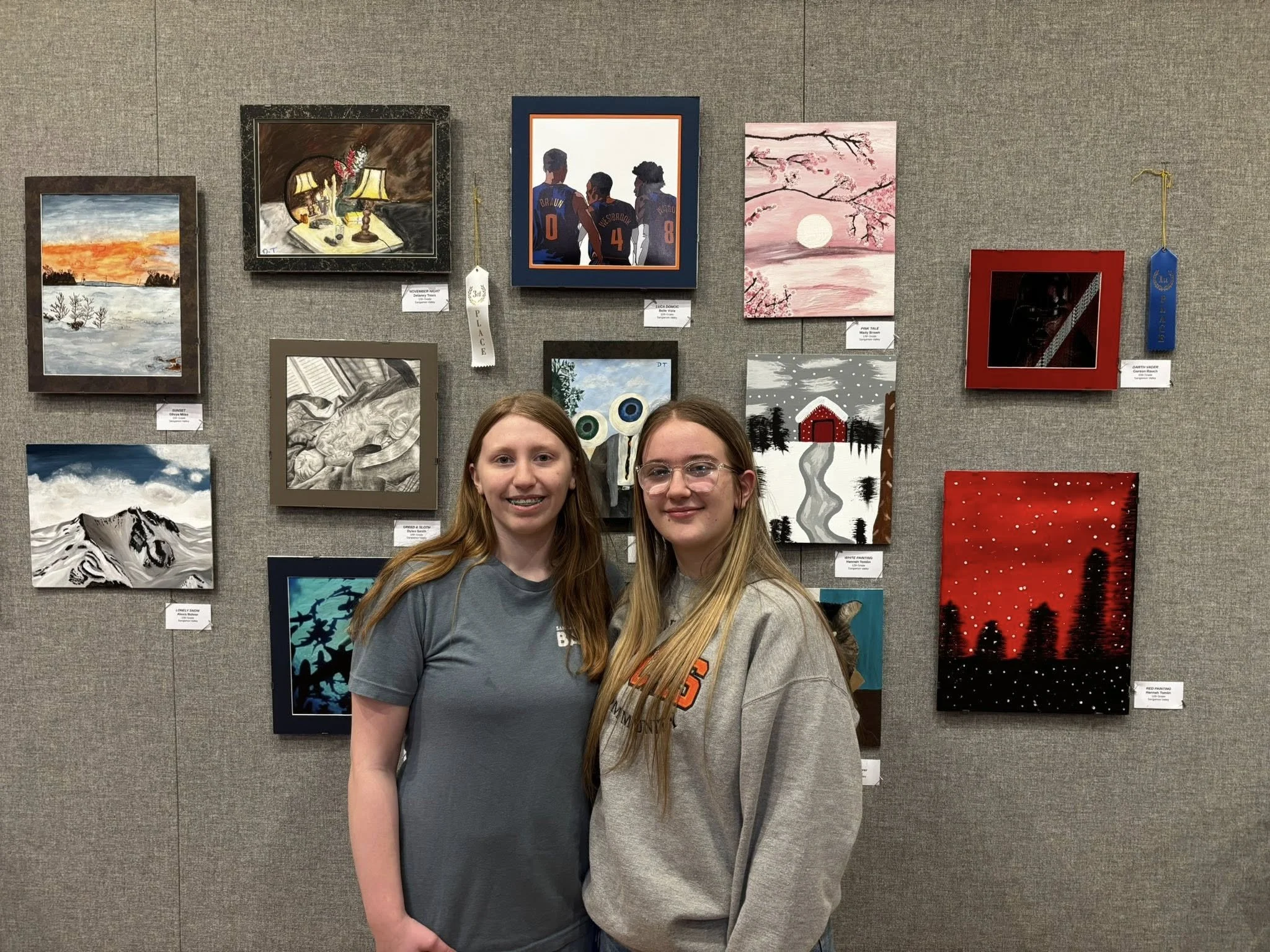 Art students stand in front of an exhibit of their work.
