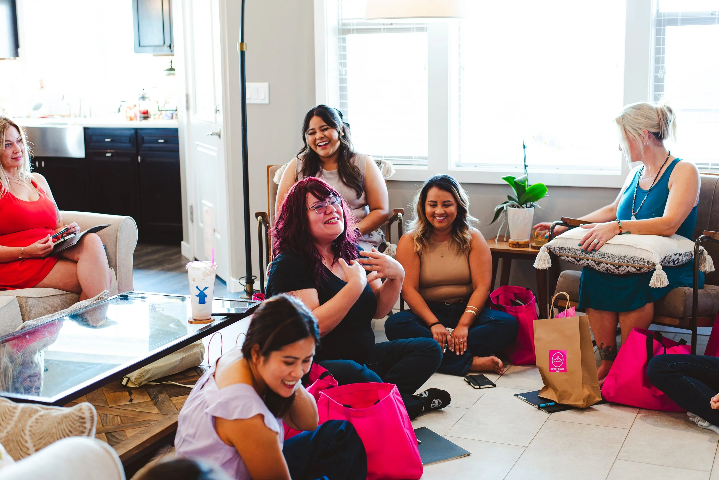 Women sitting around a living room laughing at a retreat.