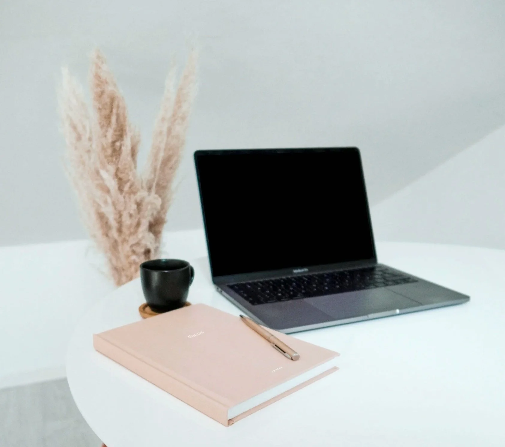 Laptop with pink planner and coffee to get ready for the New Year