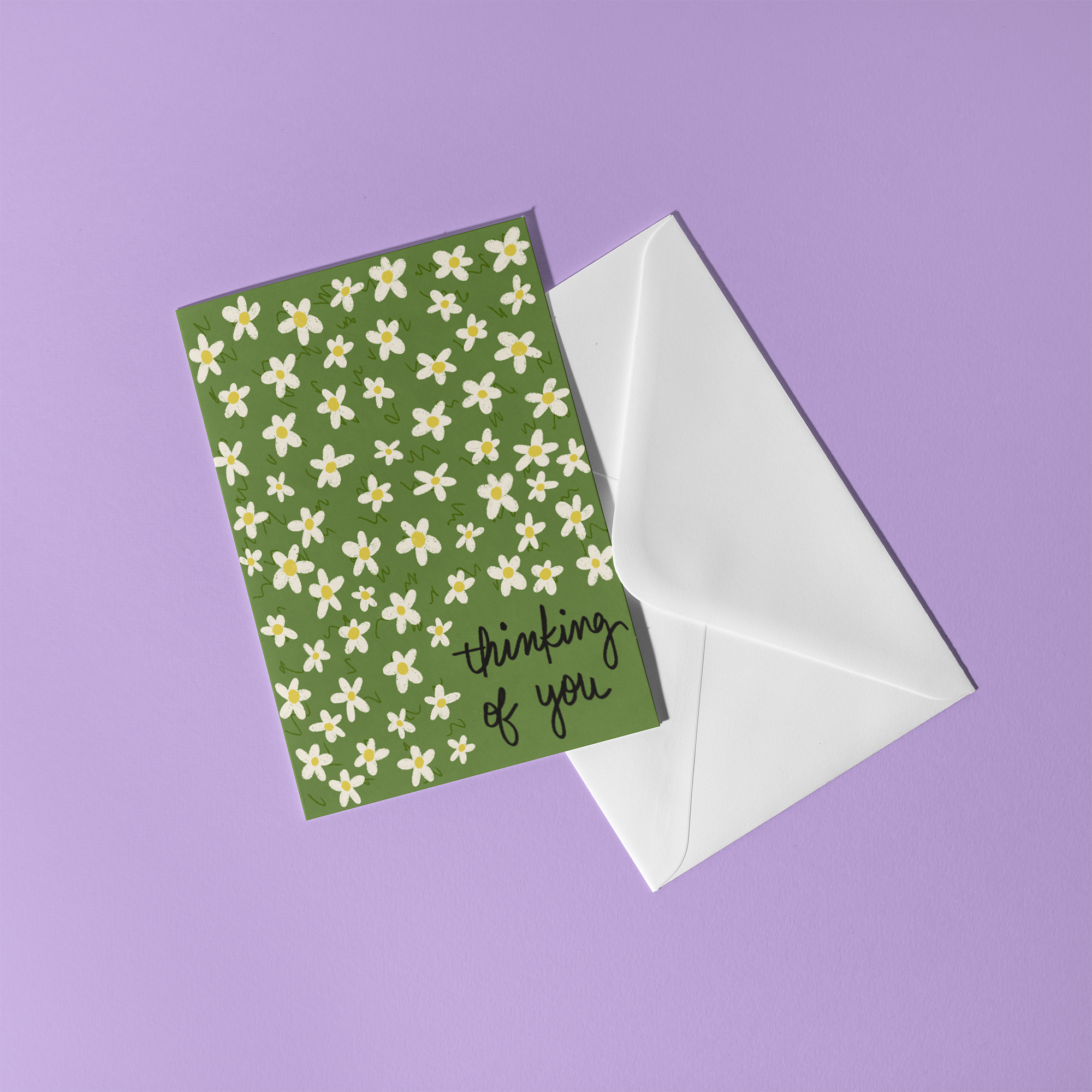 Greeting card with a green background and a daisy pattern, reading "Thinking of you"