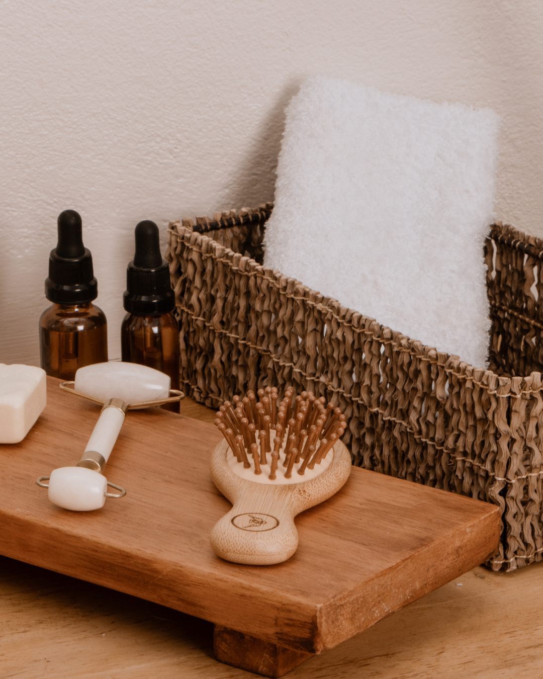 Hair brush, jade roller, skincare, and hand towel on counter
