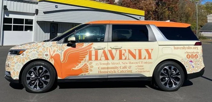 A vehicle with a colorful wrap advertising Havenly, a community cafe in New Haven, Connecticut, offering halal, vegan, homestyle catering, and more.
