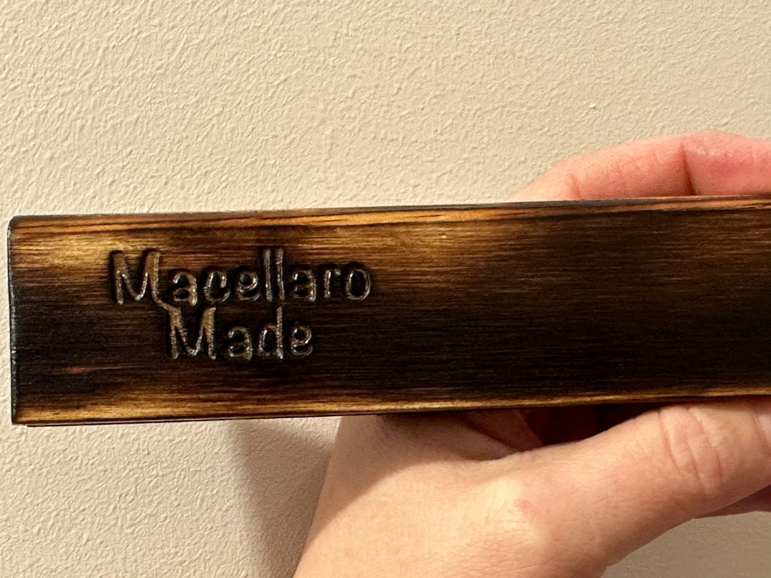 Close-up of a wooden object with the engraved text "Mecellaro Made".