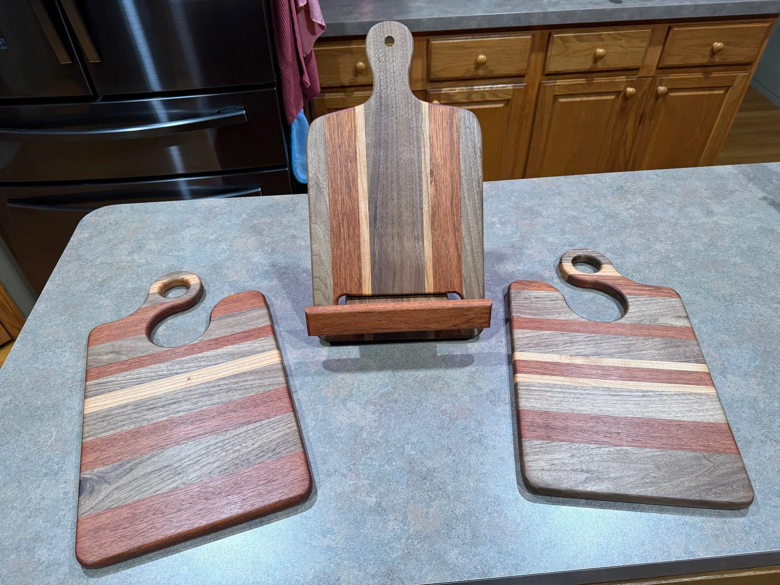 a set of three wooden boards (receipt stand, 2 charcuterie boards) on a kitchen countertop.