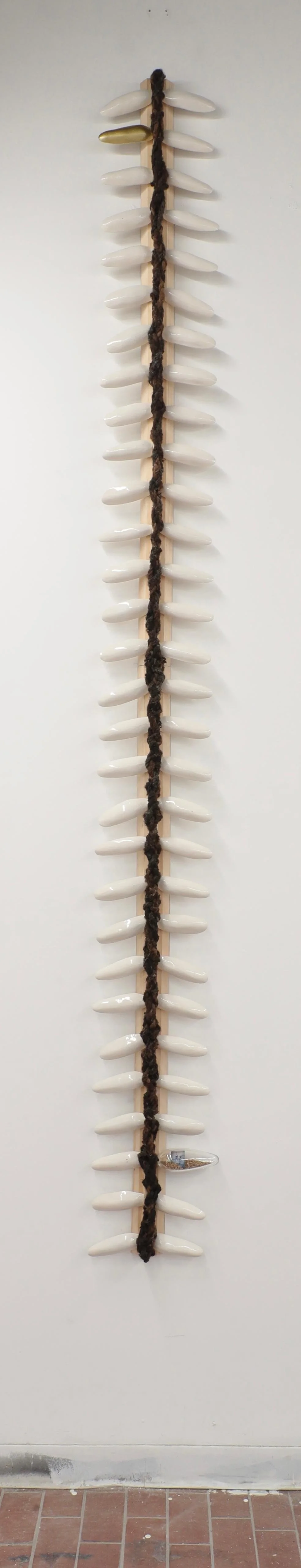 Backbone,
2026.
120” x 15” x 4”
Stoneware, wood, glass, hair, photo transfer, paint and rice. 
Description: The forced labor of enslaved Africans seeded the vast fortunes rice planters wrested from the land particularly in the coastal areas of Georgi