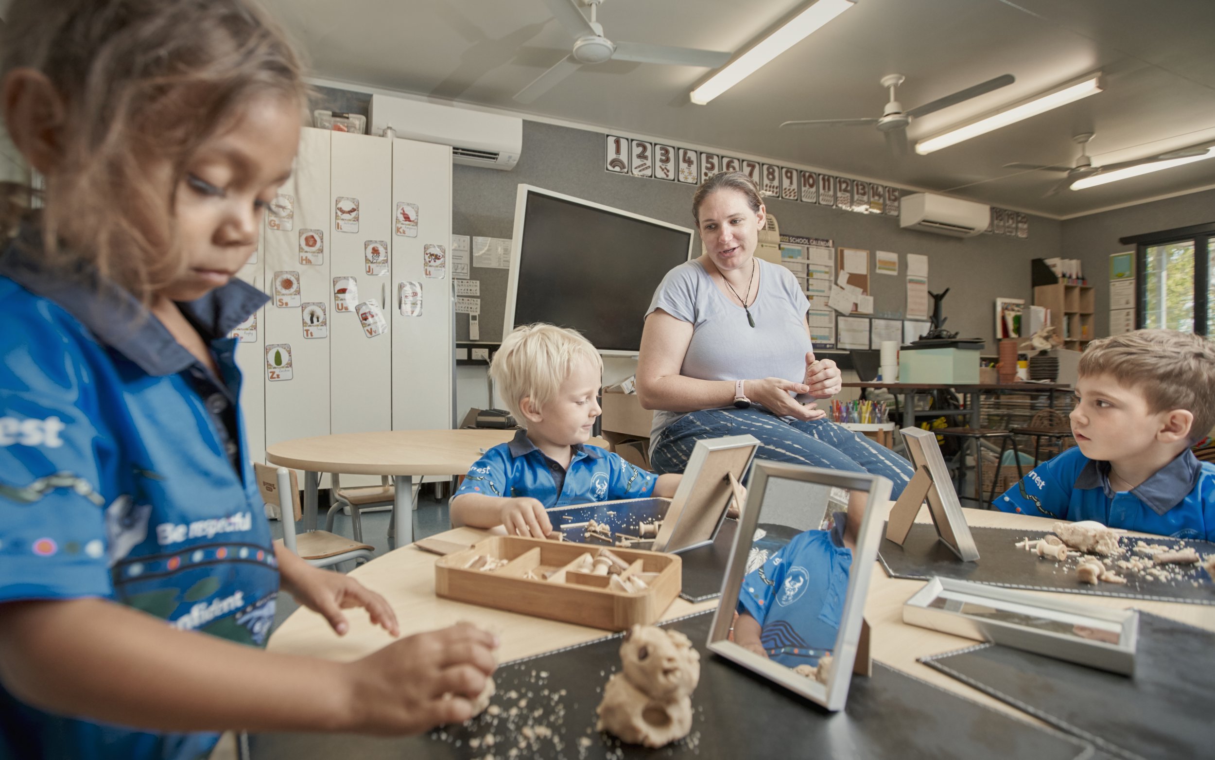 Children and teacher working on clay projects in a classroom.