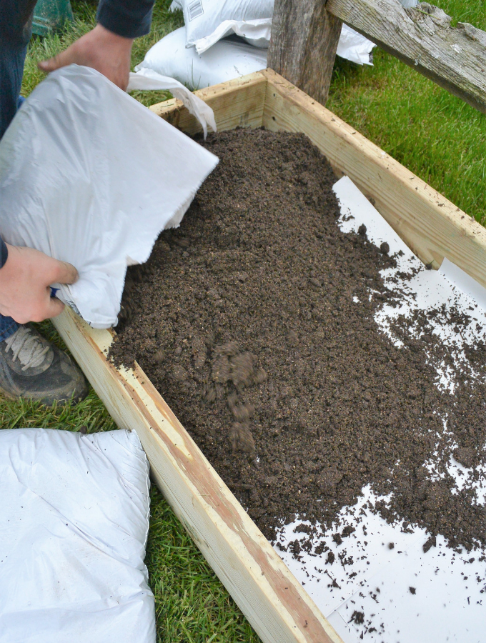 pouring top soil and garden soil into the raised bed