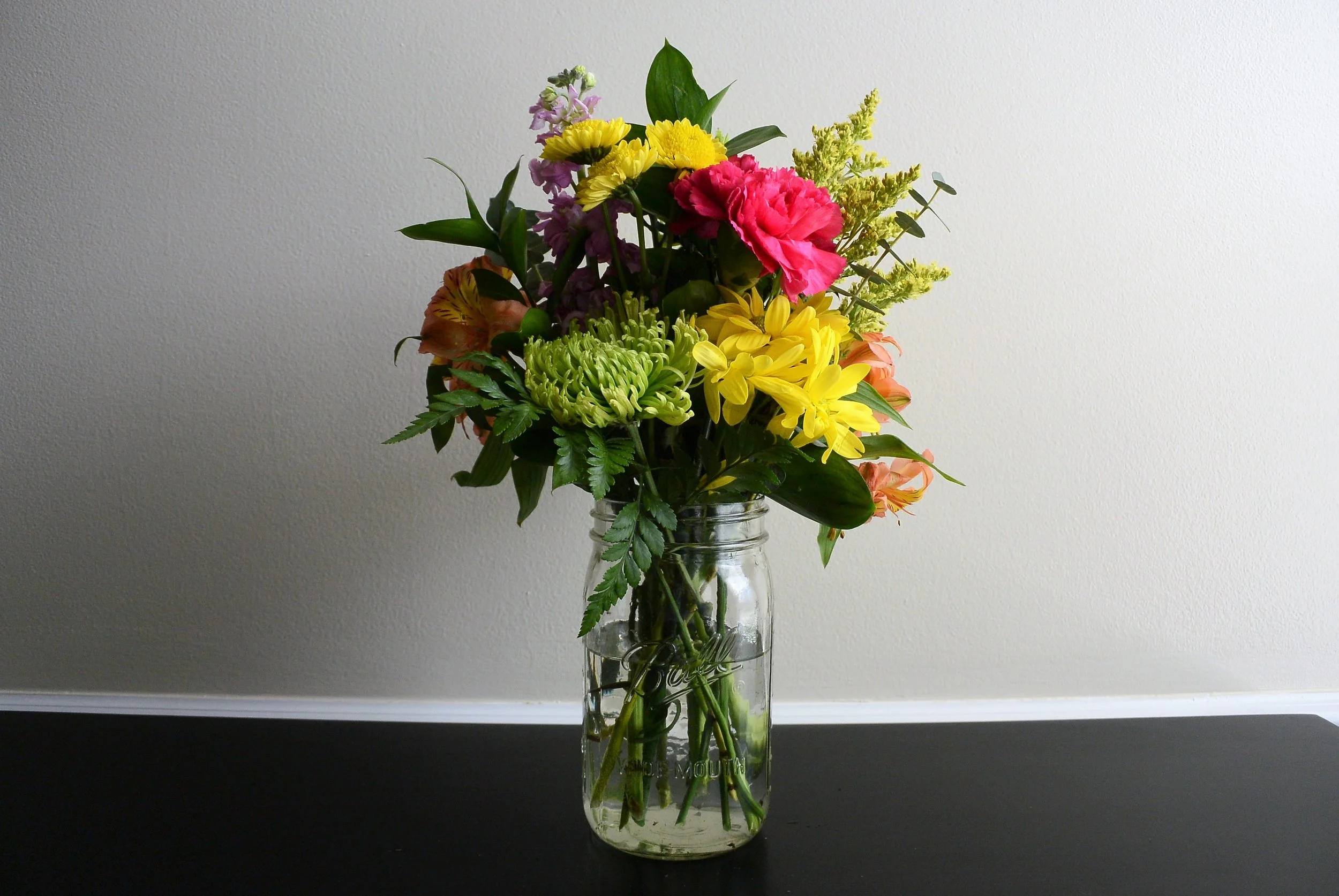 mason jar with greens and flowers and filler added