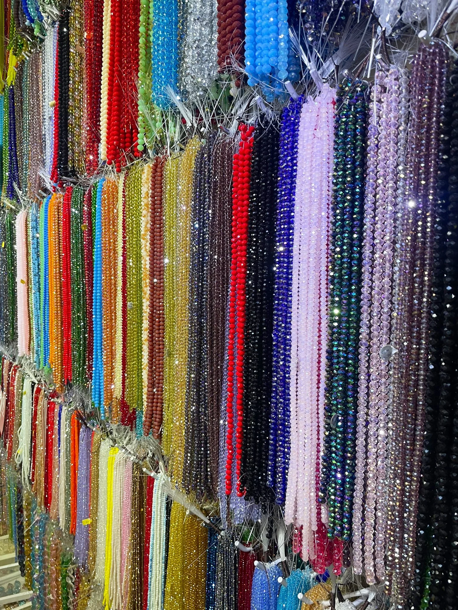 Colorful strands of beads and jewelry hanging on a display rack.