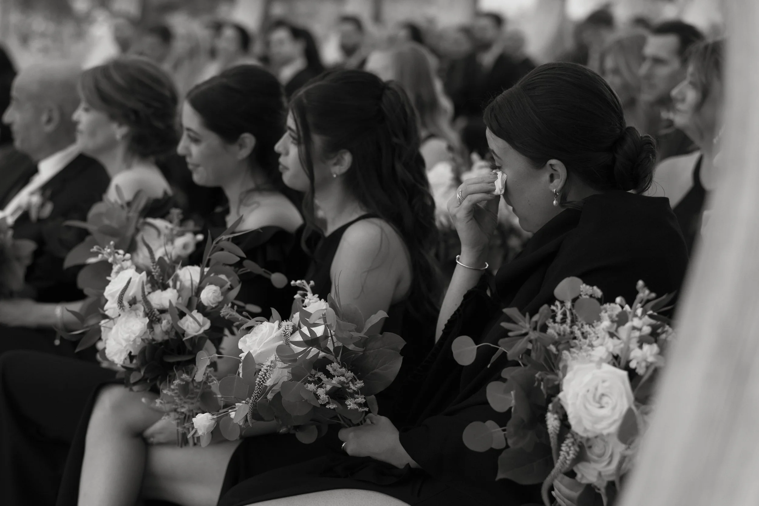 Bridesmaids watching wedding ceremony with one wiping tears