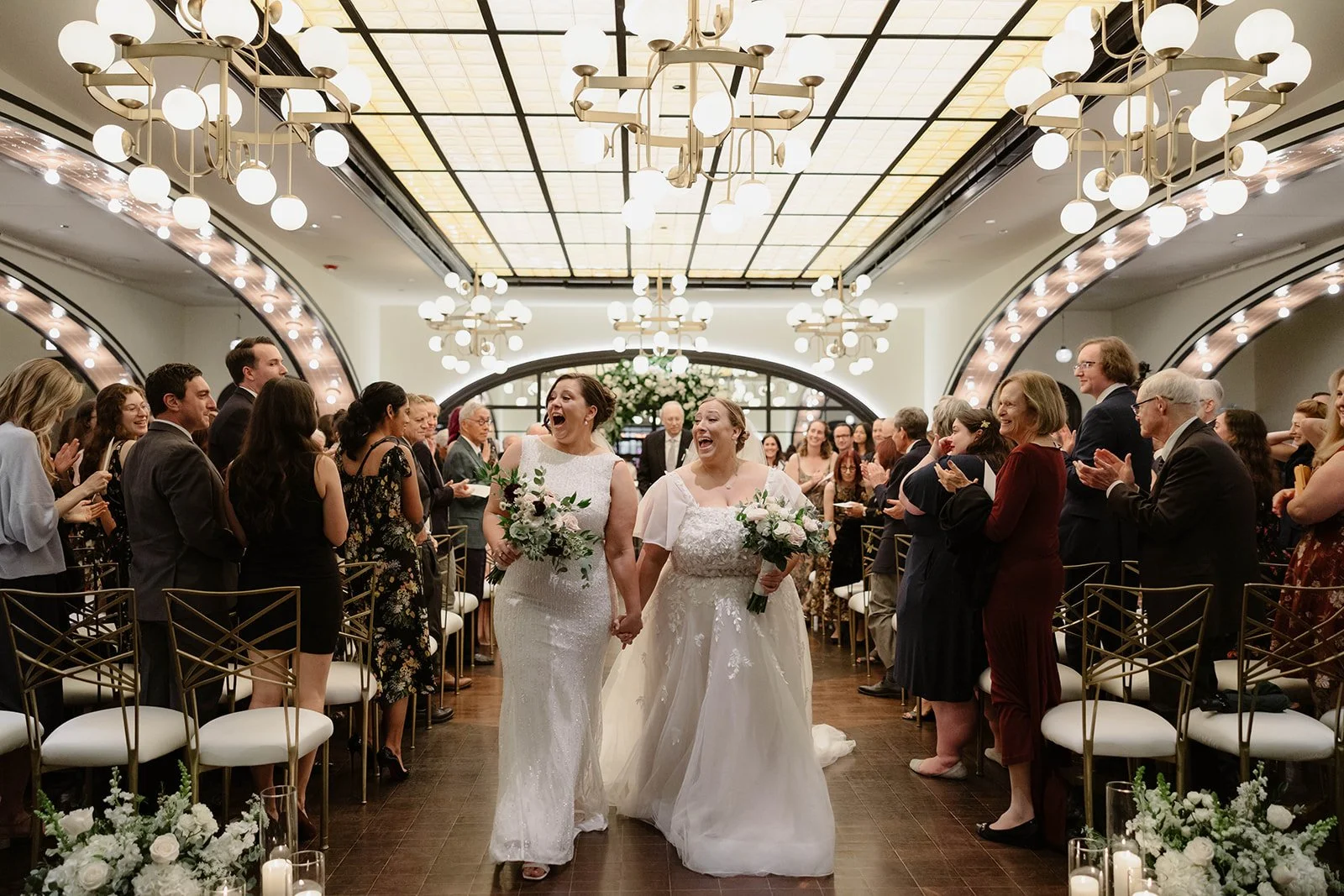 Two brides smiling walking out of their wedding ceremony