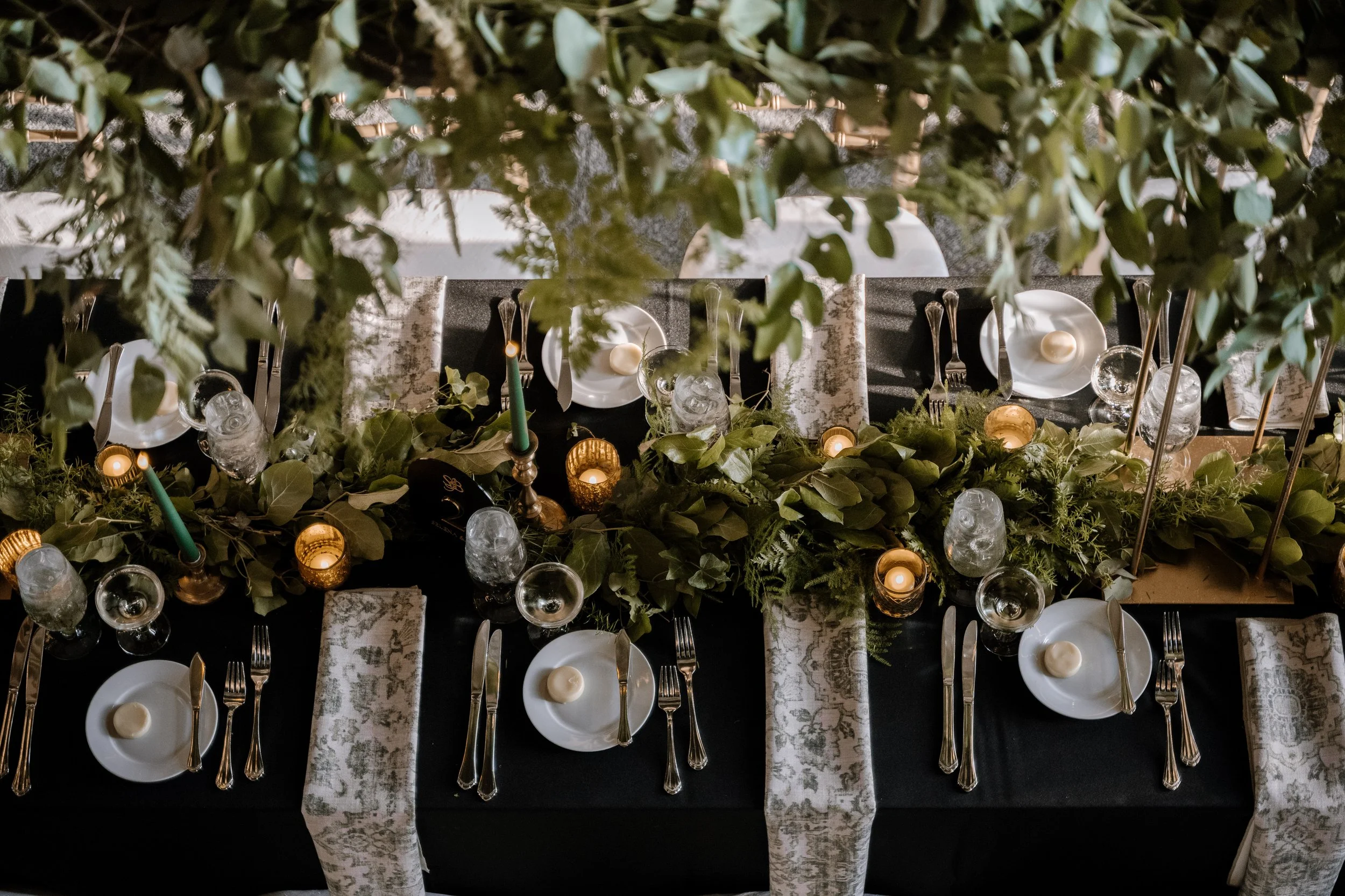 Wedding reception table at The Library at 190 with greenery, candles, and tableware, viewed from above.