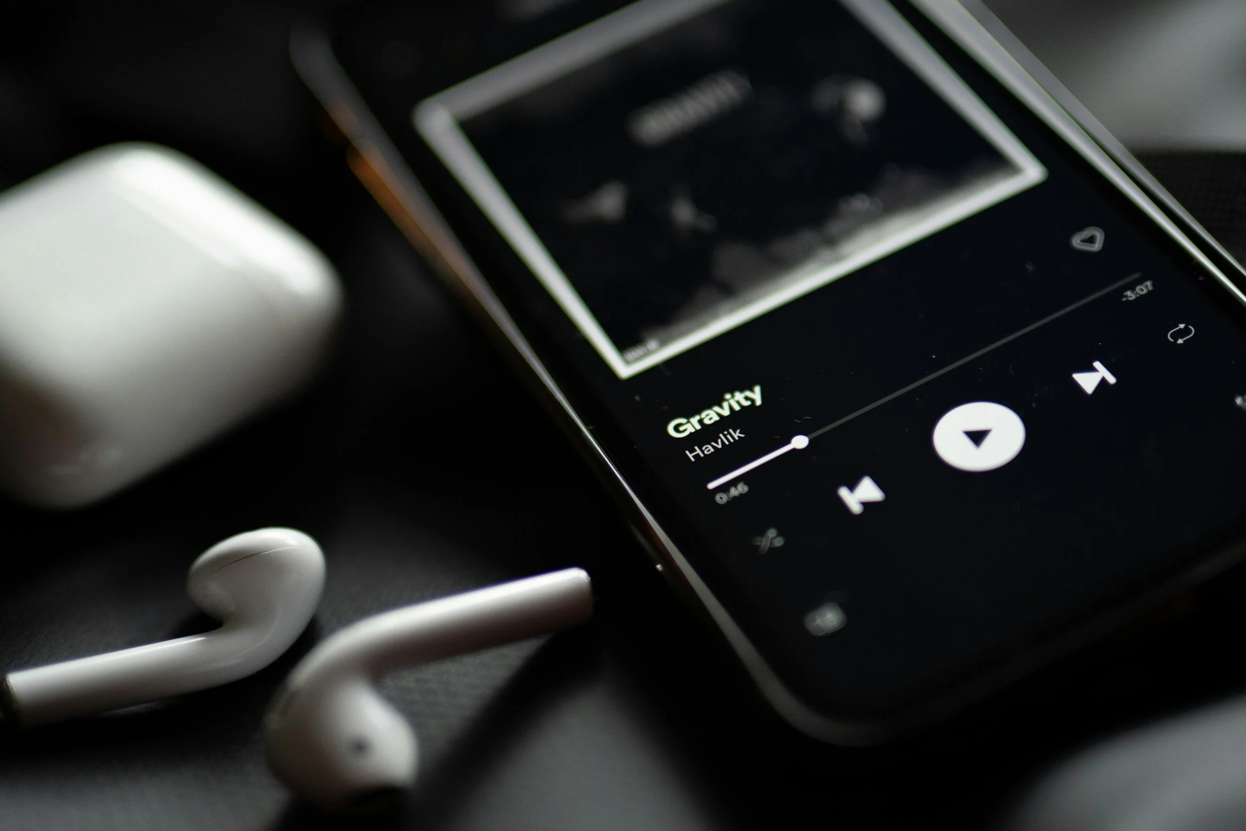 Smartphone showing a music streaming app next to wireless earbuds