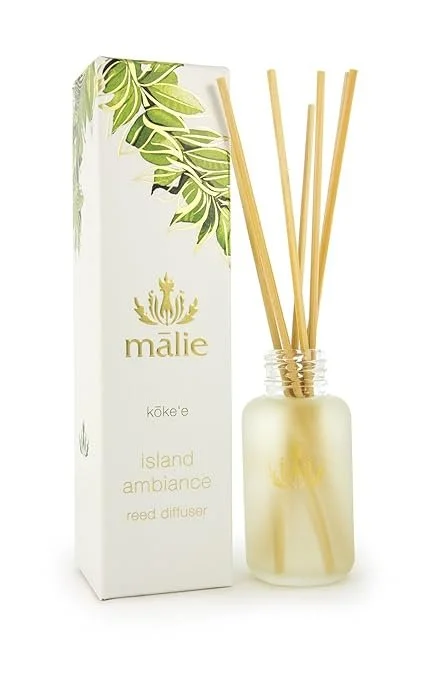 Malie Island Ambiance Reed Diffuser with bamboo reeds in a frosted glass jar, next to its packaging box featuring green leaves and gold accents.