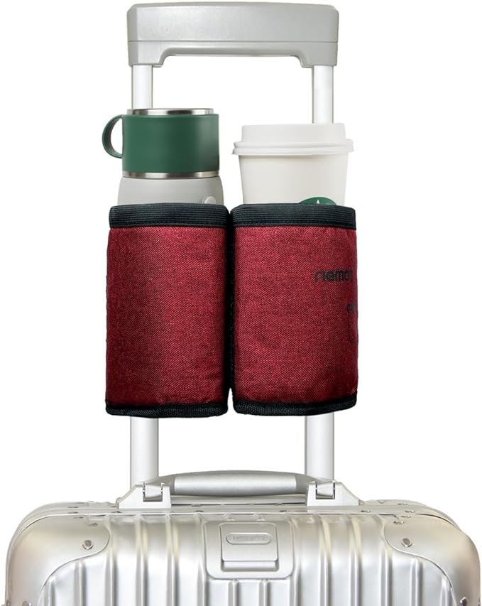 A luggage cart carrying a silver suitcase with a built-in handle, two red fabric bottle holders attached to the side, and two beverage containers - a white disposable coffee cup and a green reusable cup with a lid.