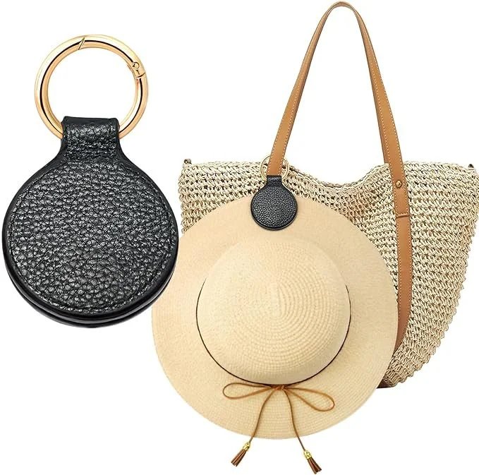 A black textured leather round handbag with a gold ring handle, a beige woven tote bag with leather straps, and a beige sun hat with a black circular attachment.
