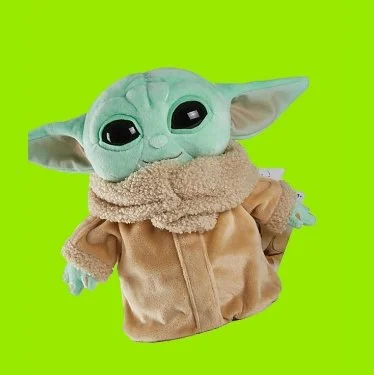 Cute plush toy of Baby Yoda from The Mandalorian wearing a beige jacket and a fluffy beige scarf, against a bright green background.
