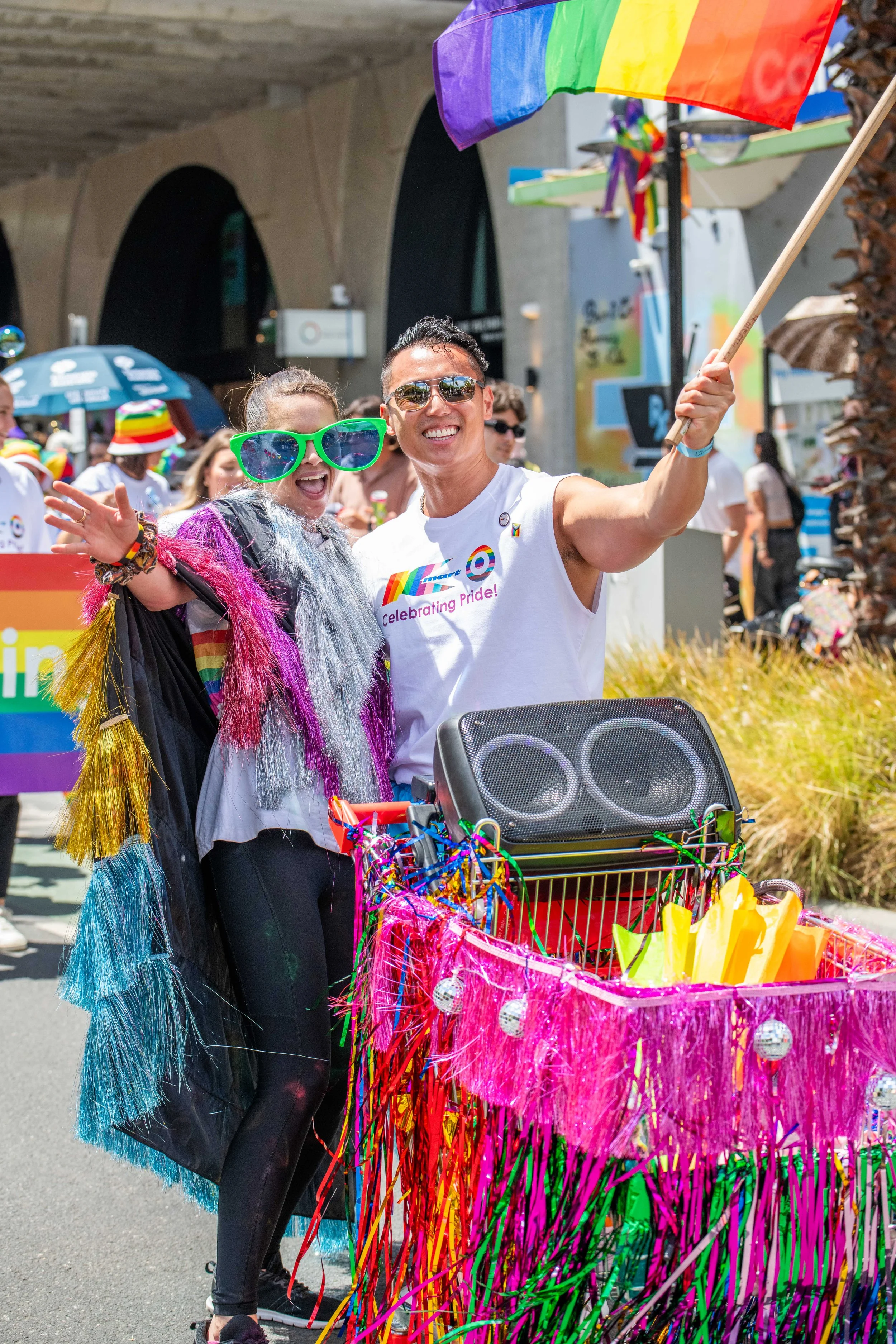 Two humans with a large speaker in a trolley smile at the camera.