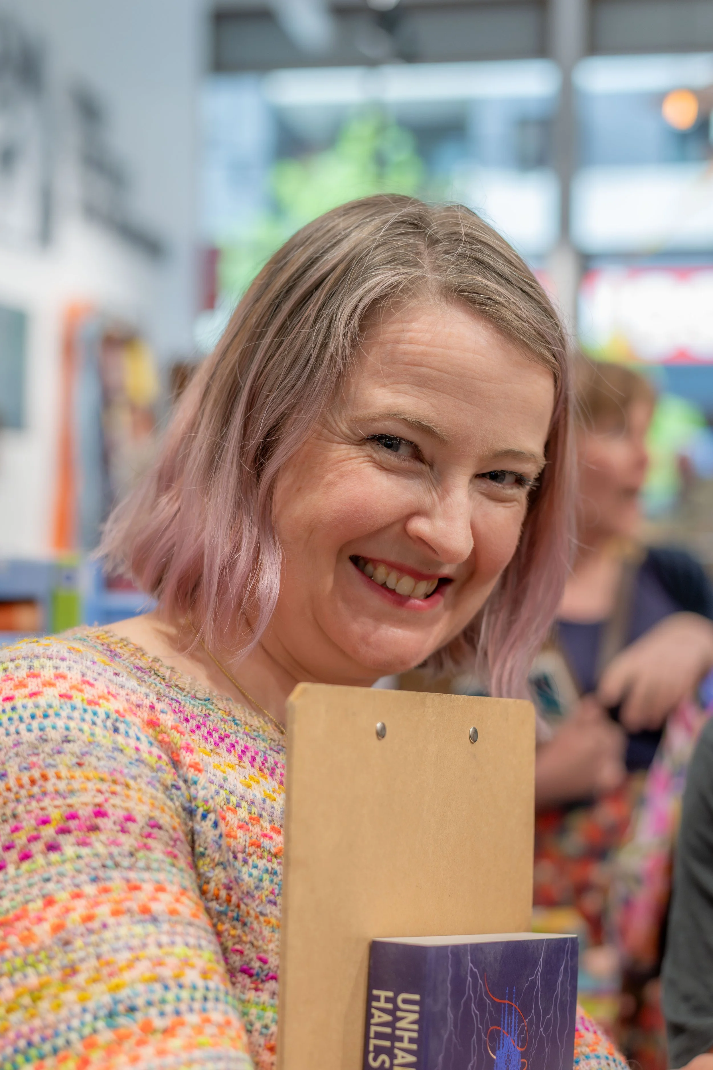 An author holding a clipboard smiles at the camera.